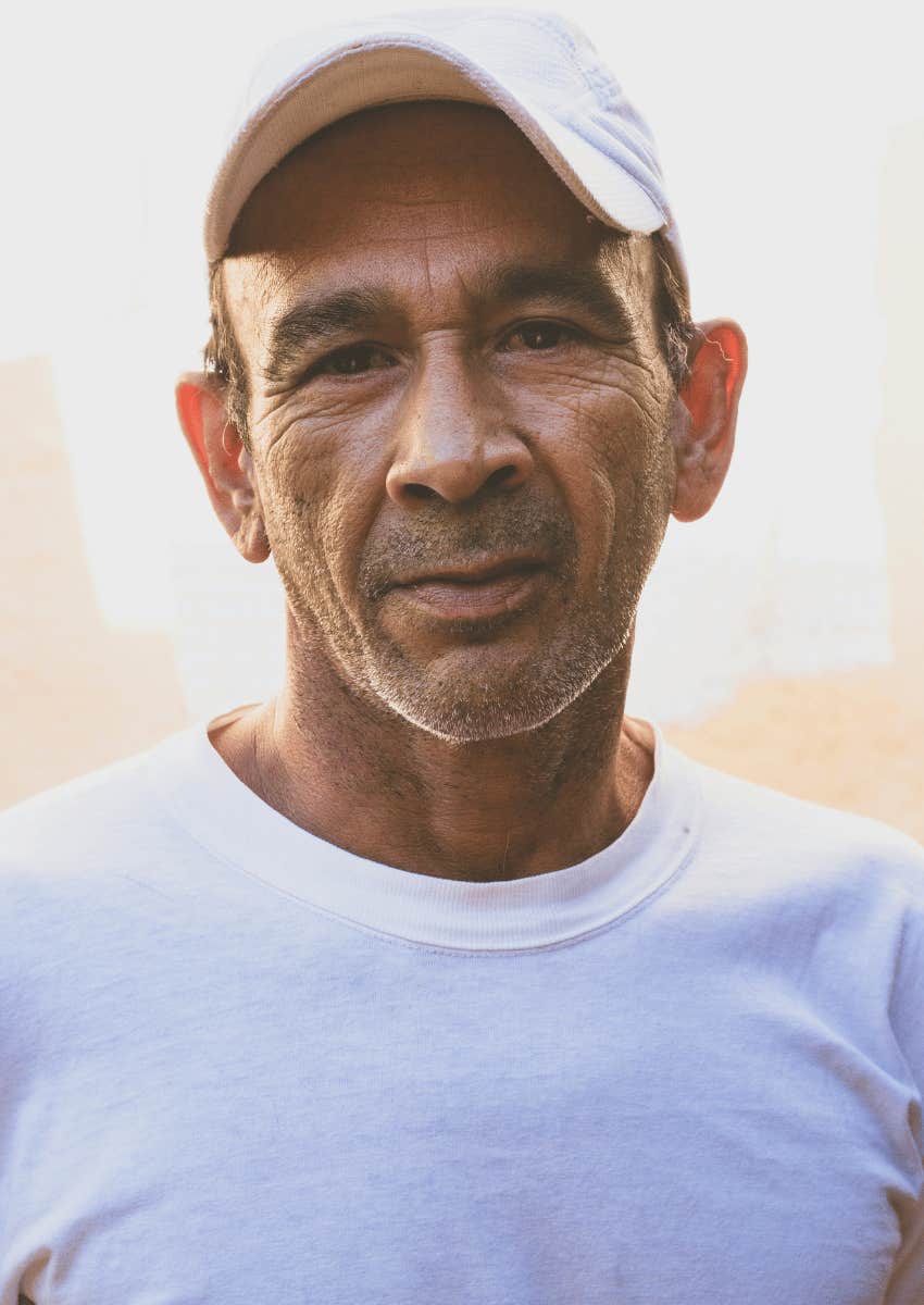 older man with a serious expression wearing a hat