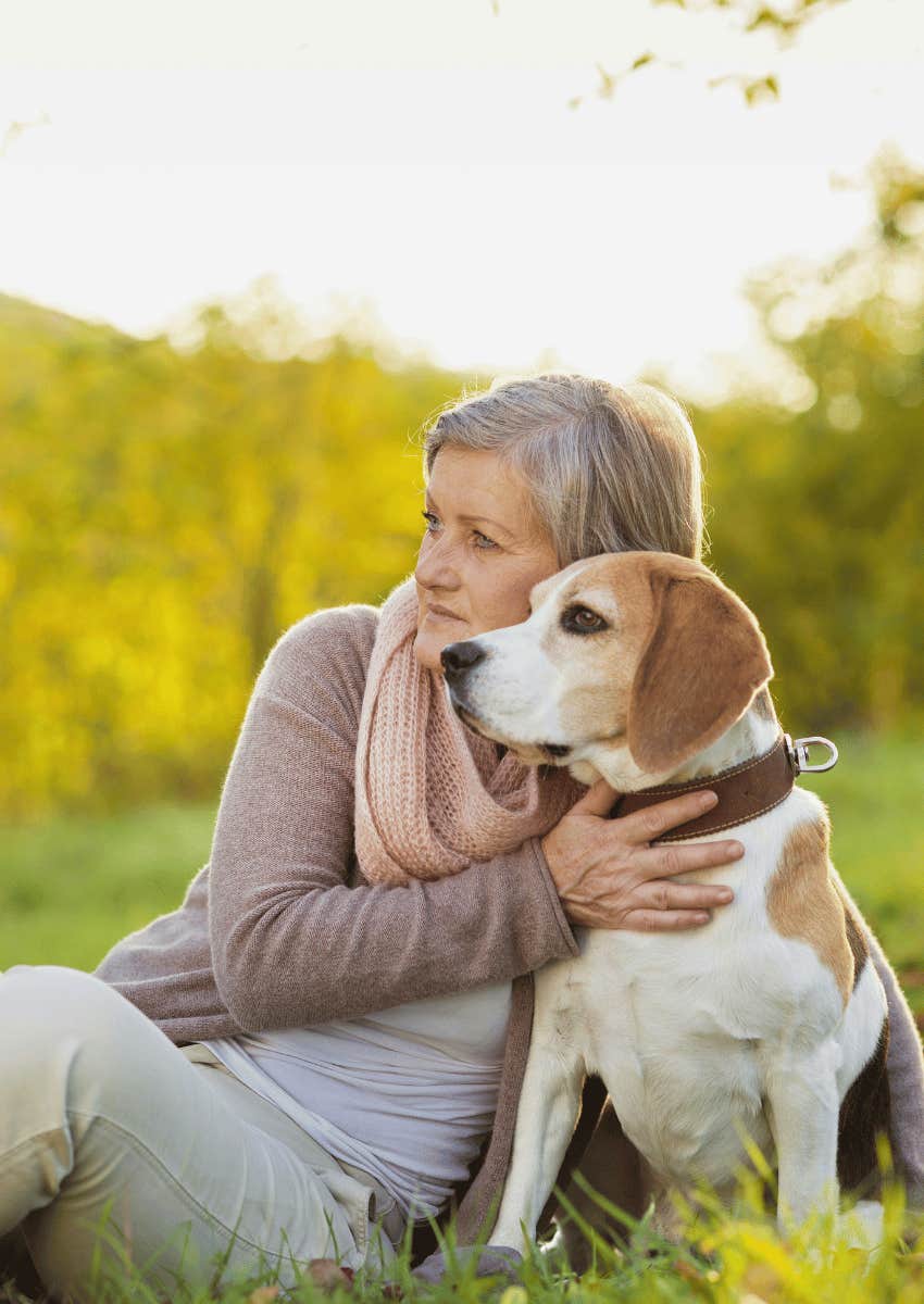 older woman sitting outdoors next to her dog