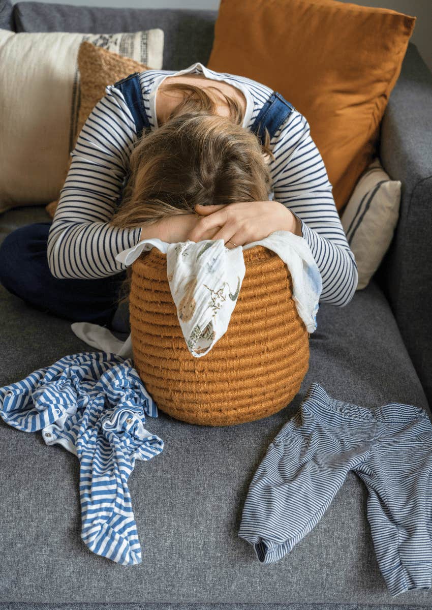 overwhelmed mom with her head in a laundry basket
