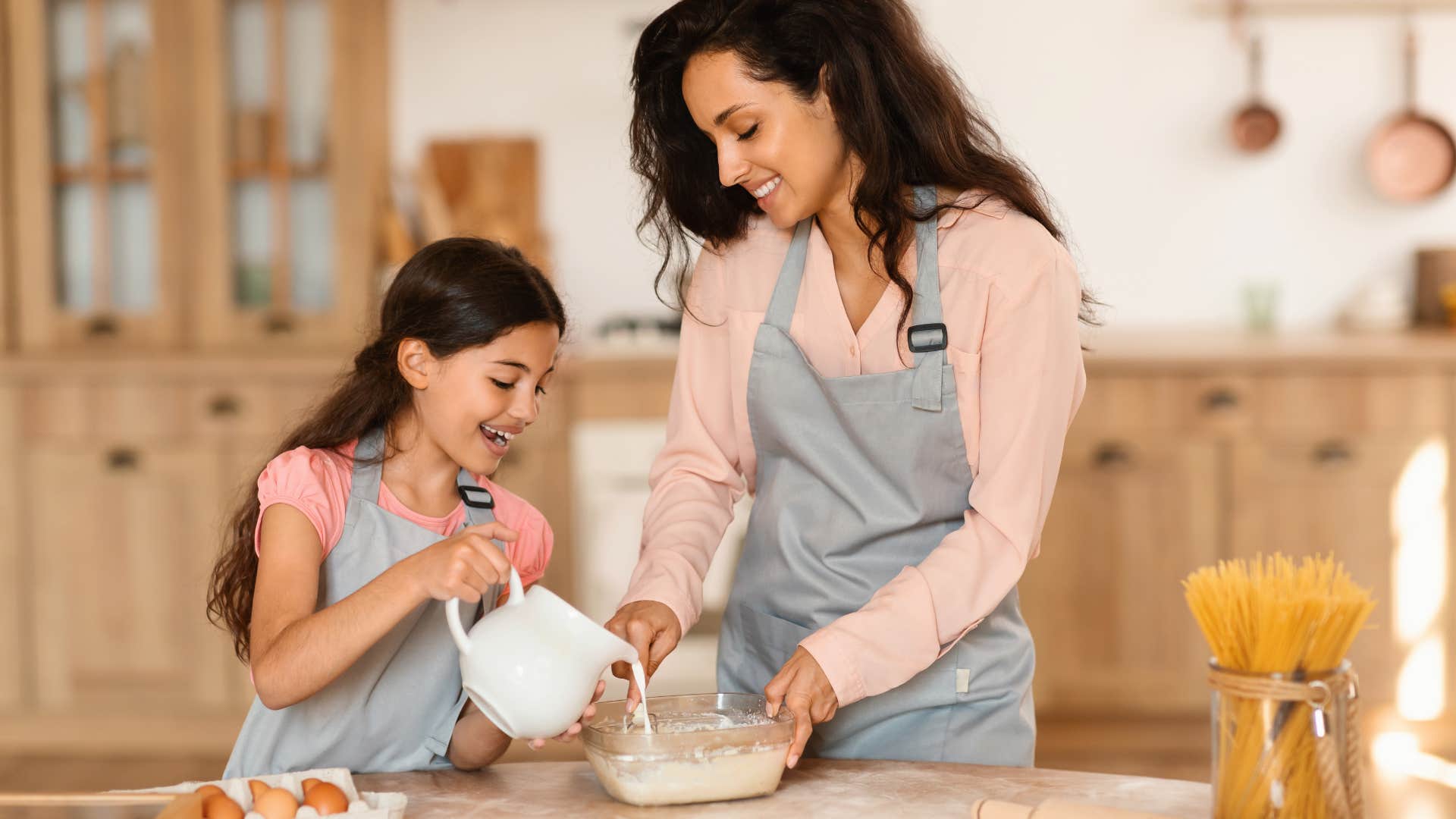 modern mom cooking with daughter in kitchen