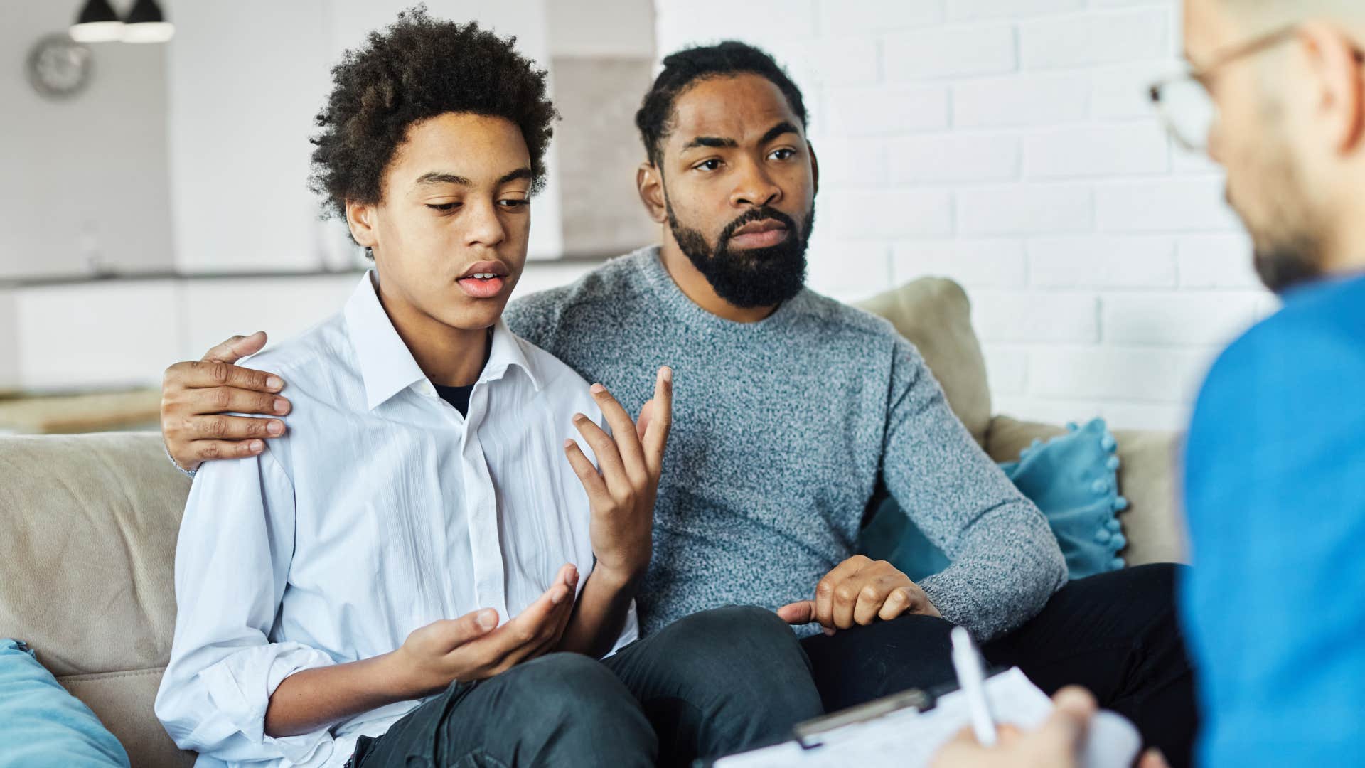 dad and teen son sitting in therapy discussing mental health openly
