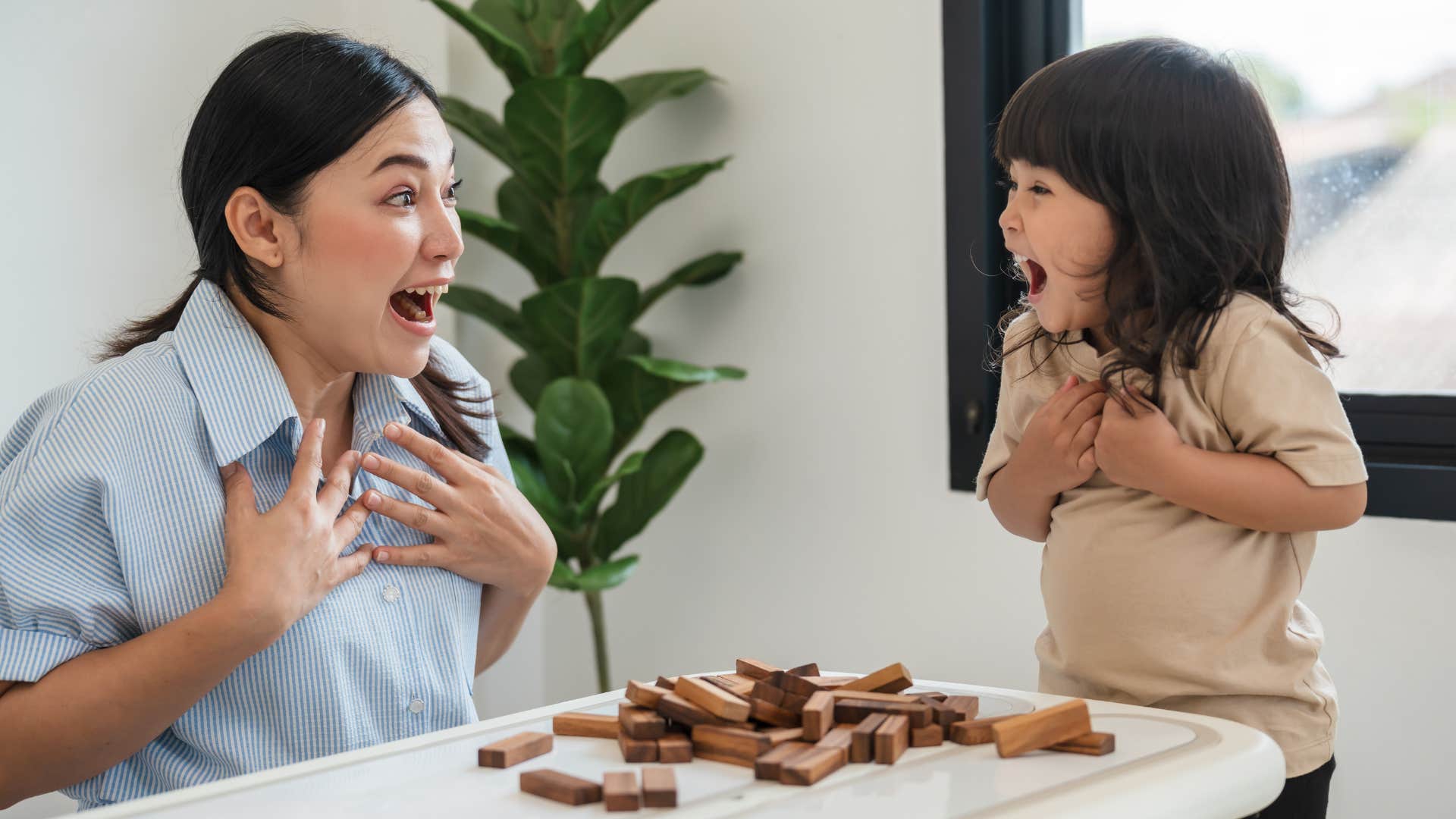 surprised kid and parent after jenga tower falls showing risk taking