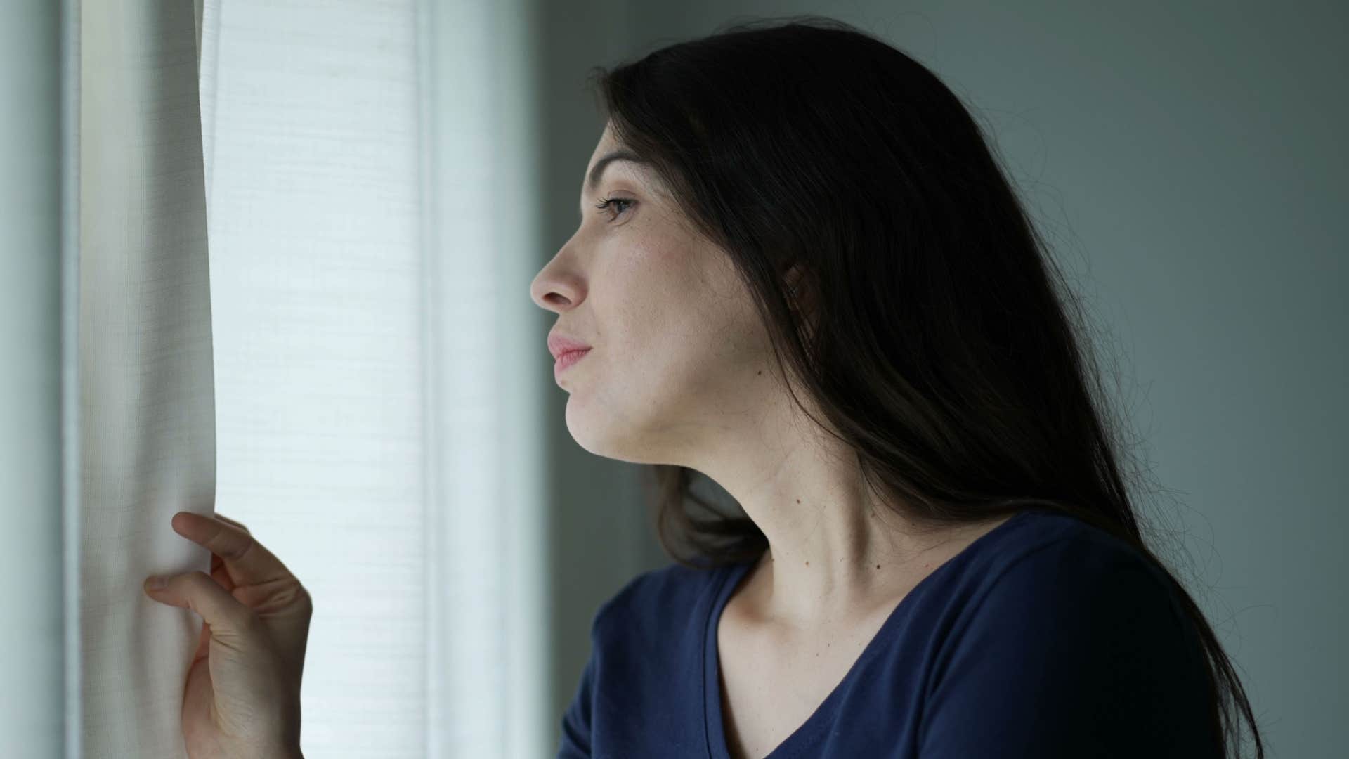 woman in dark shirt looking out window as she has strong intuition
