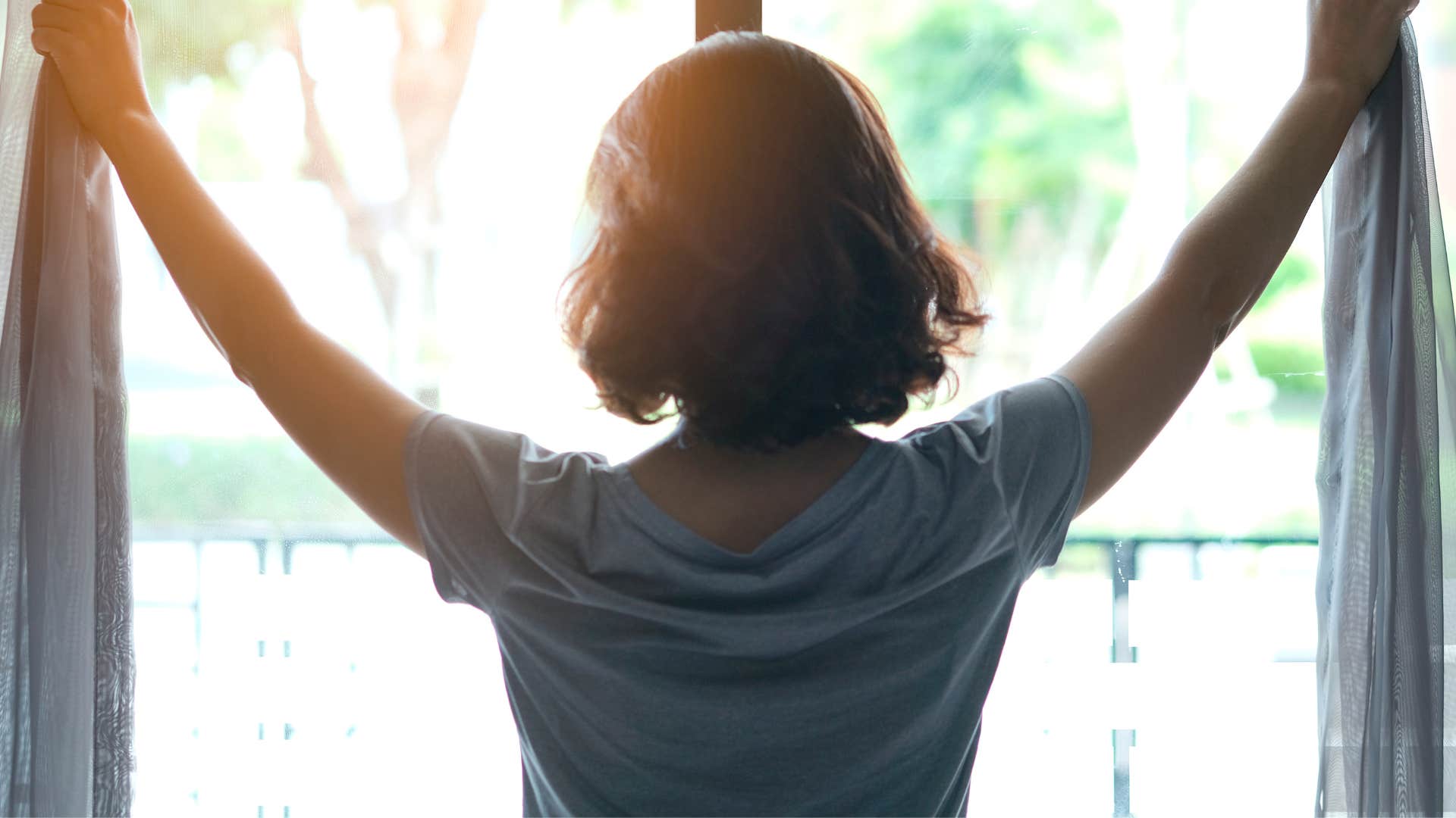 woman who is an early riser opening the curtains