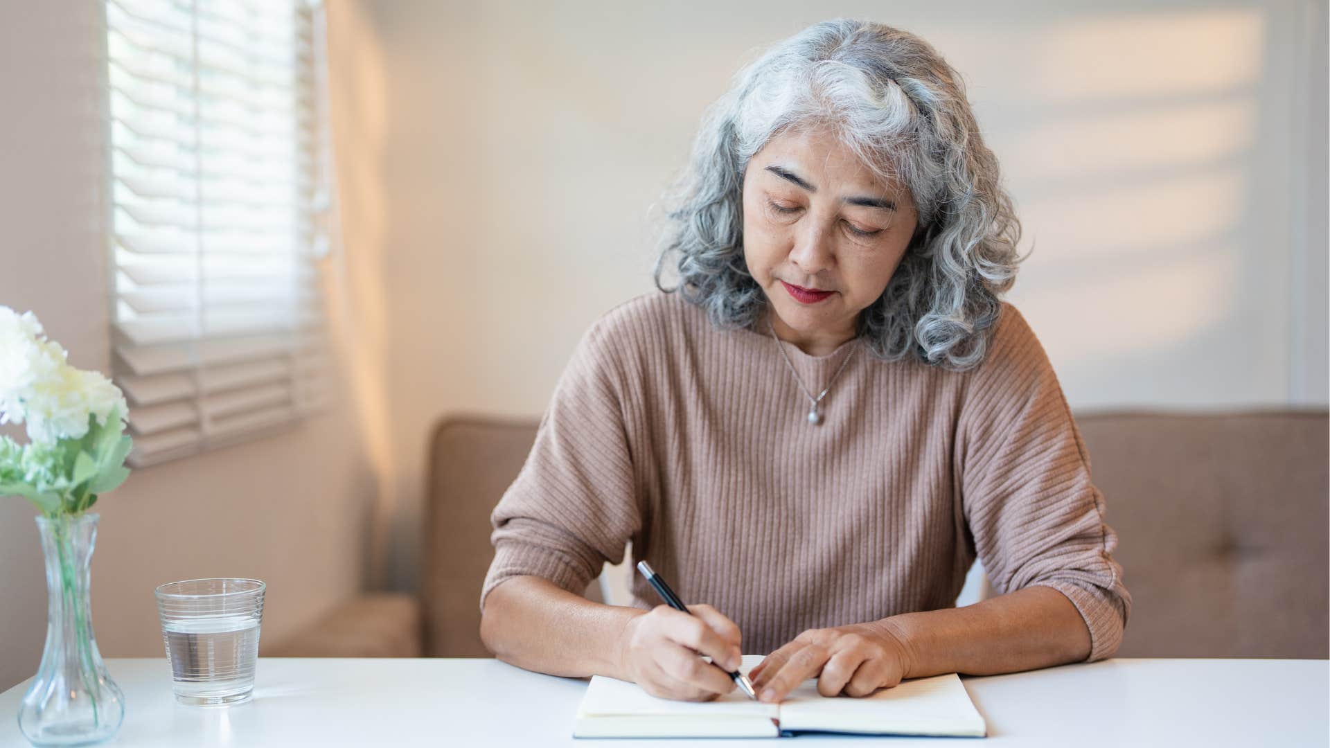 older person writes in notebook showing way to quiet mind