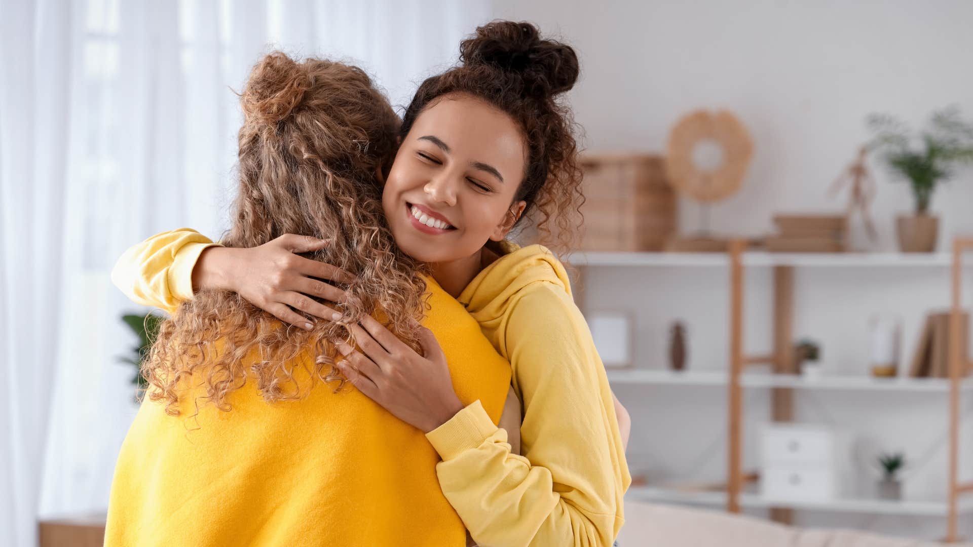 woman in yellow shirt is empathetic as she hugs friend
