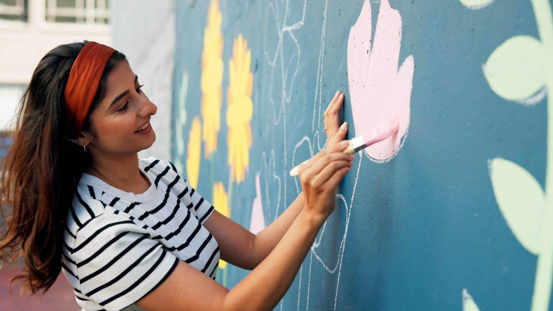woman who is easily mentally stimulated painting a mural
