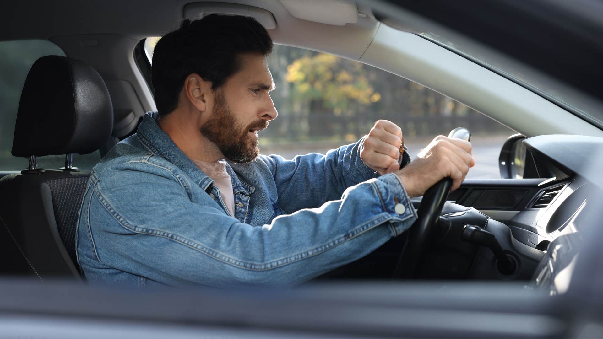impulsive man driving while looking at his watch