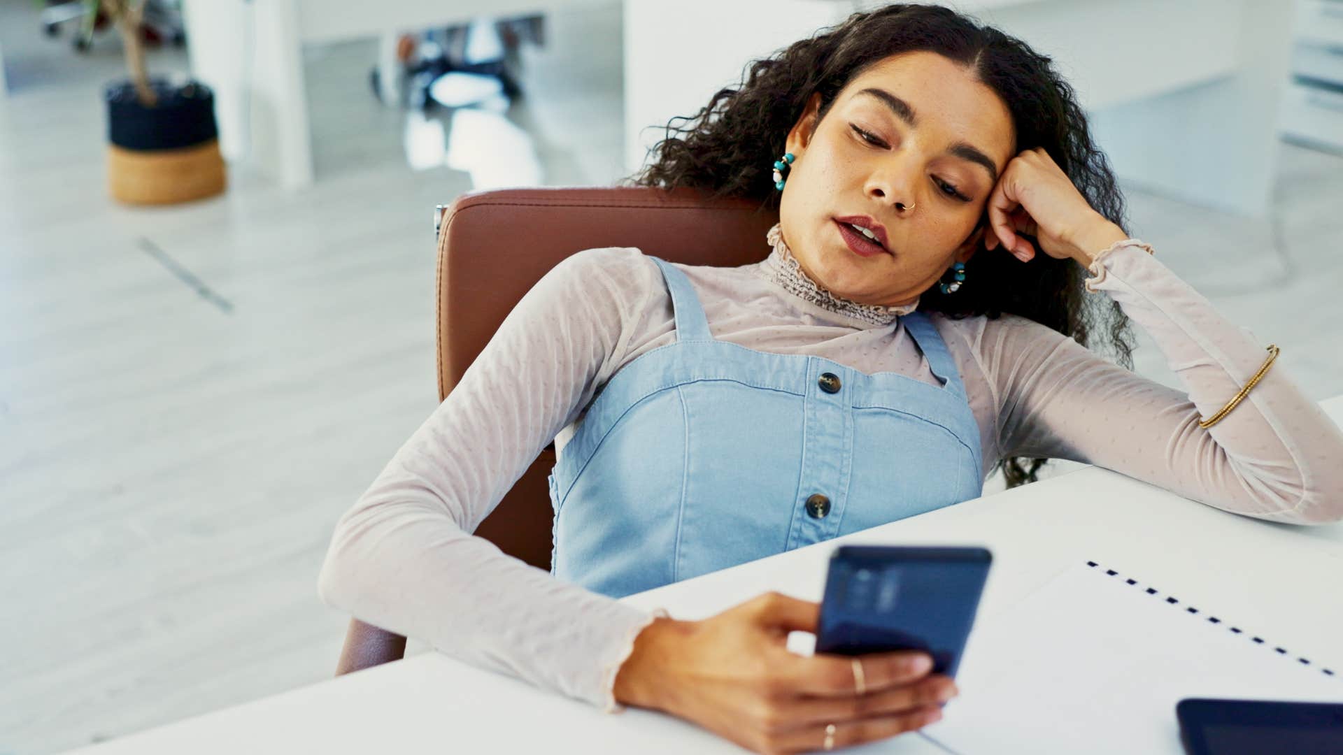 woman getting bored easily at work scrolling her phone