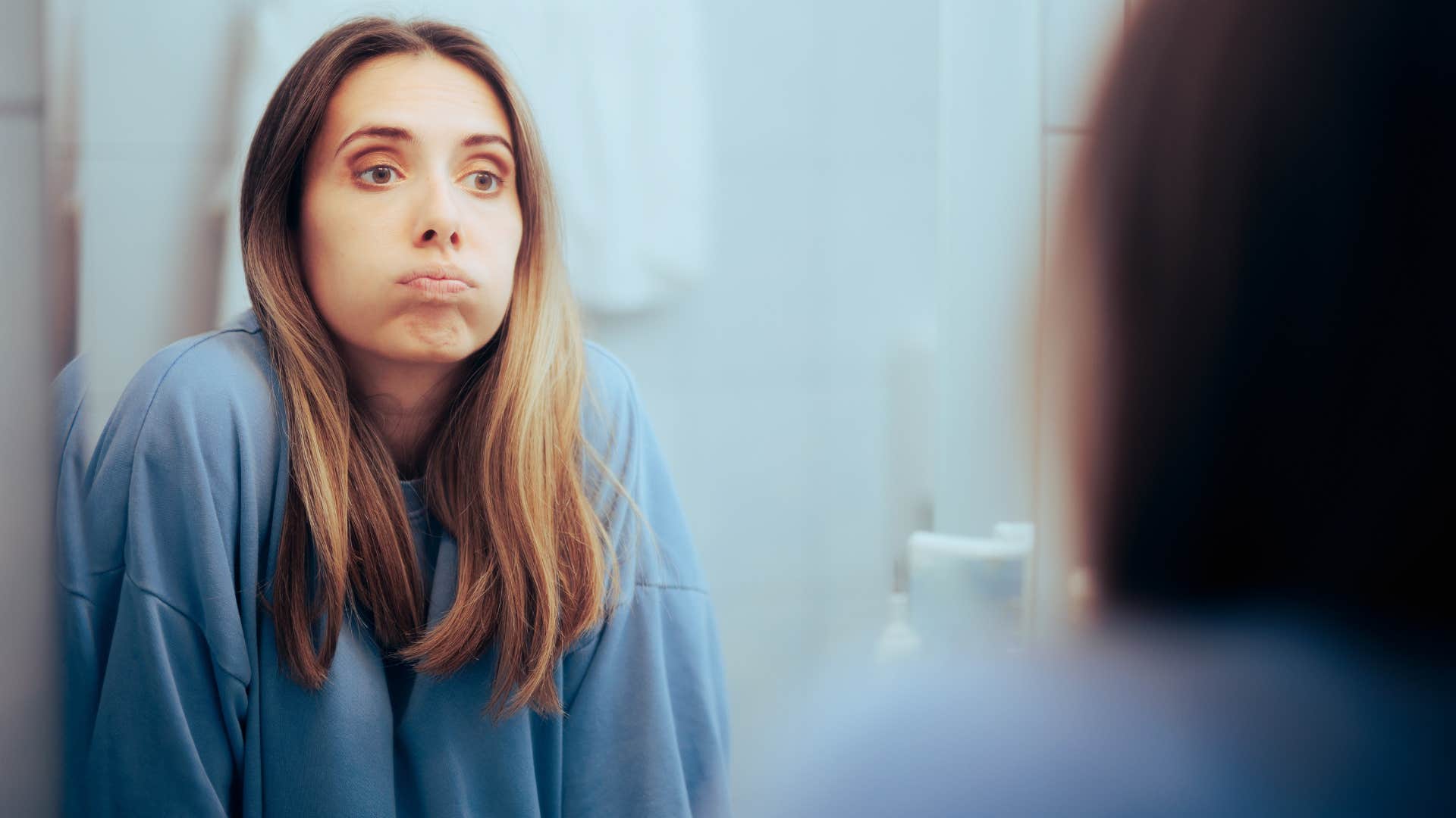 woman looking in the mirror doubting himself