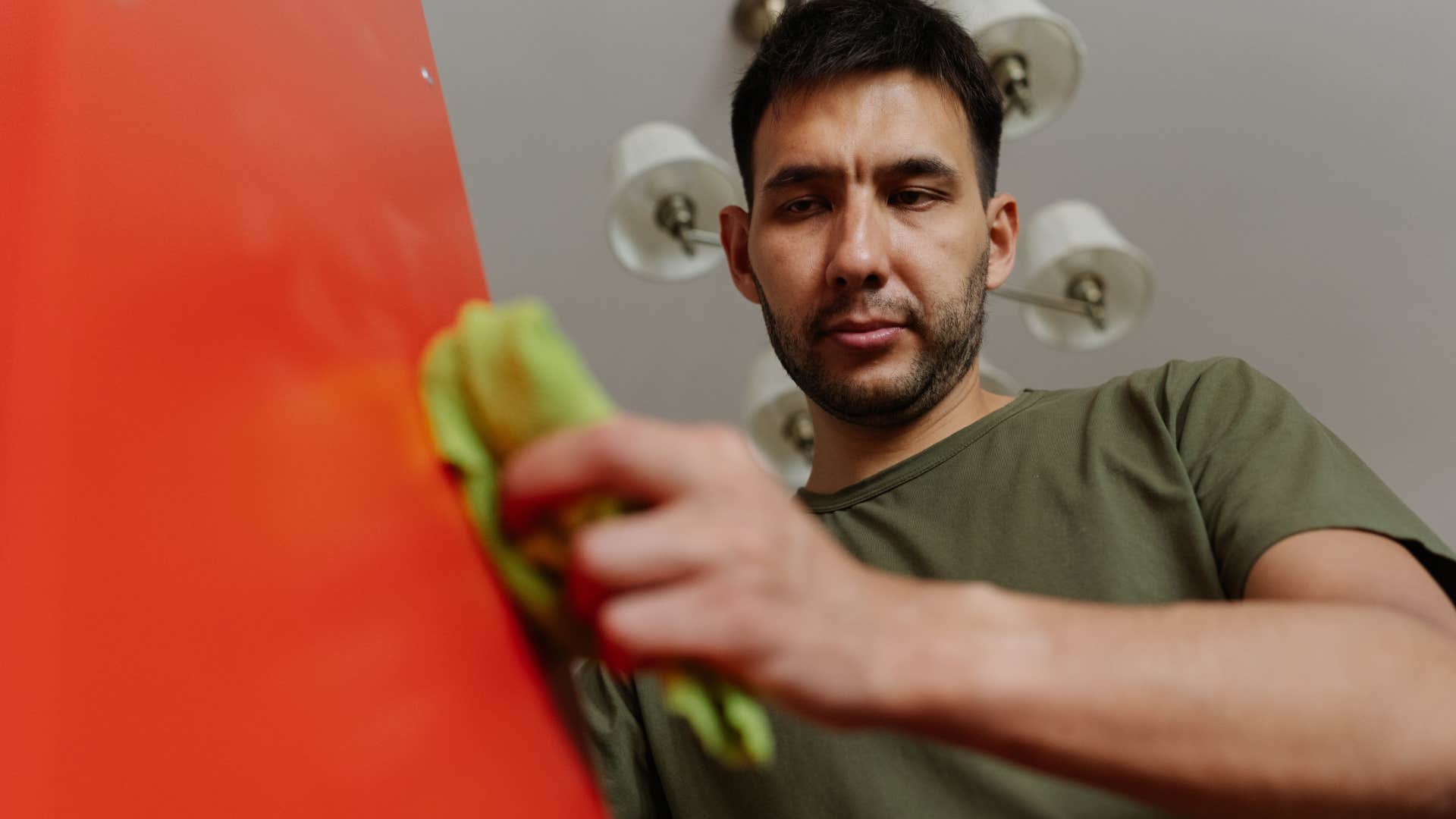 Thoughtful man cleaning at home.