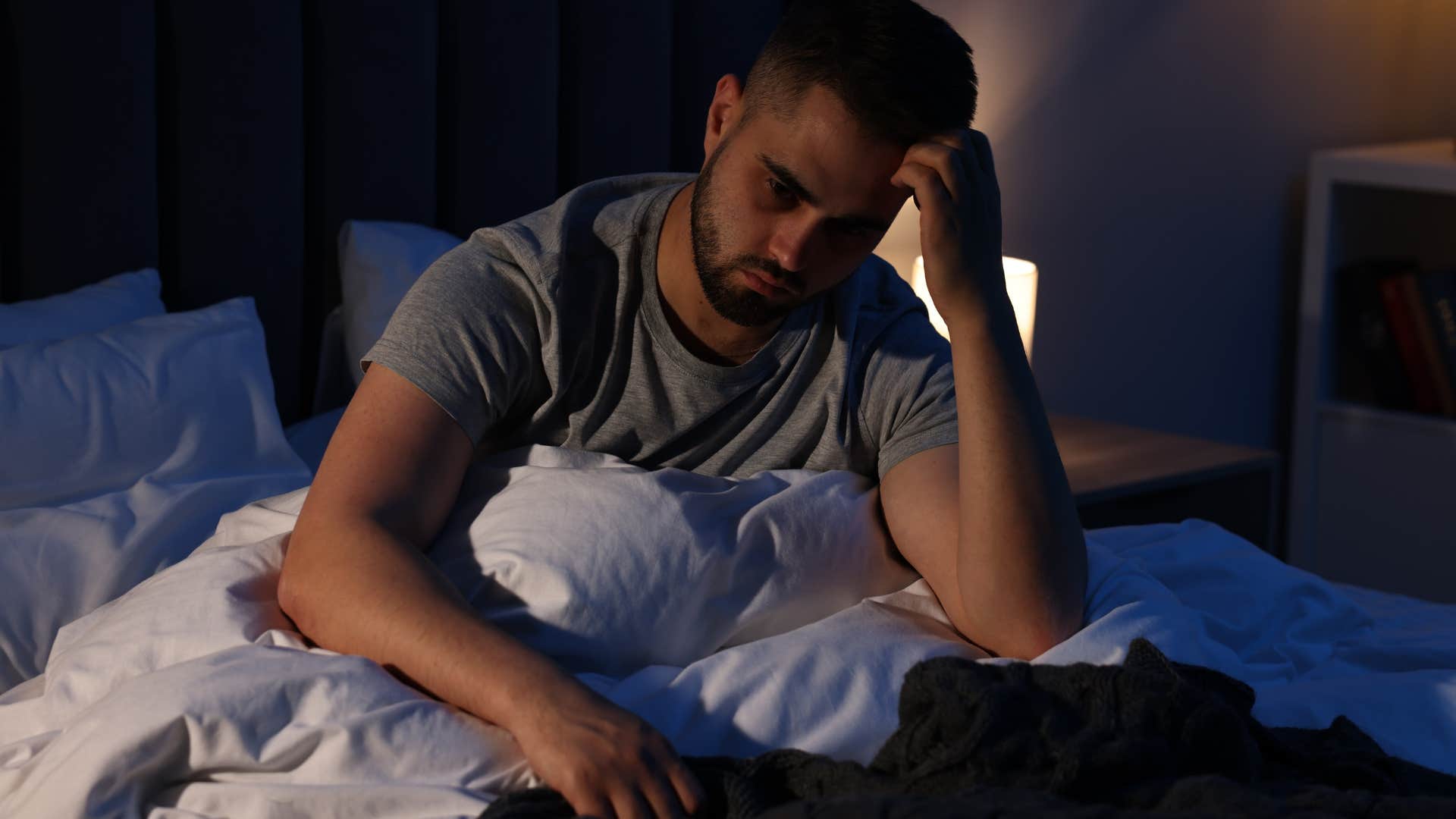 stressed man who struggles to sleep deeply in bed at night