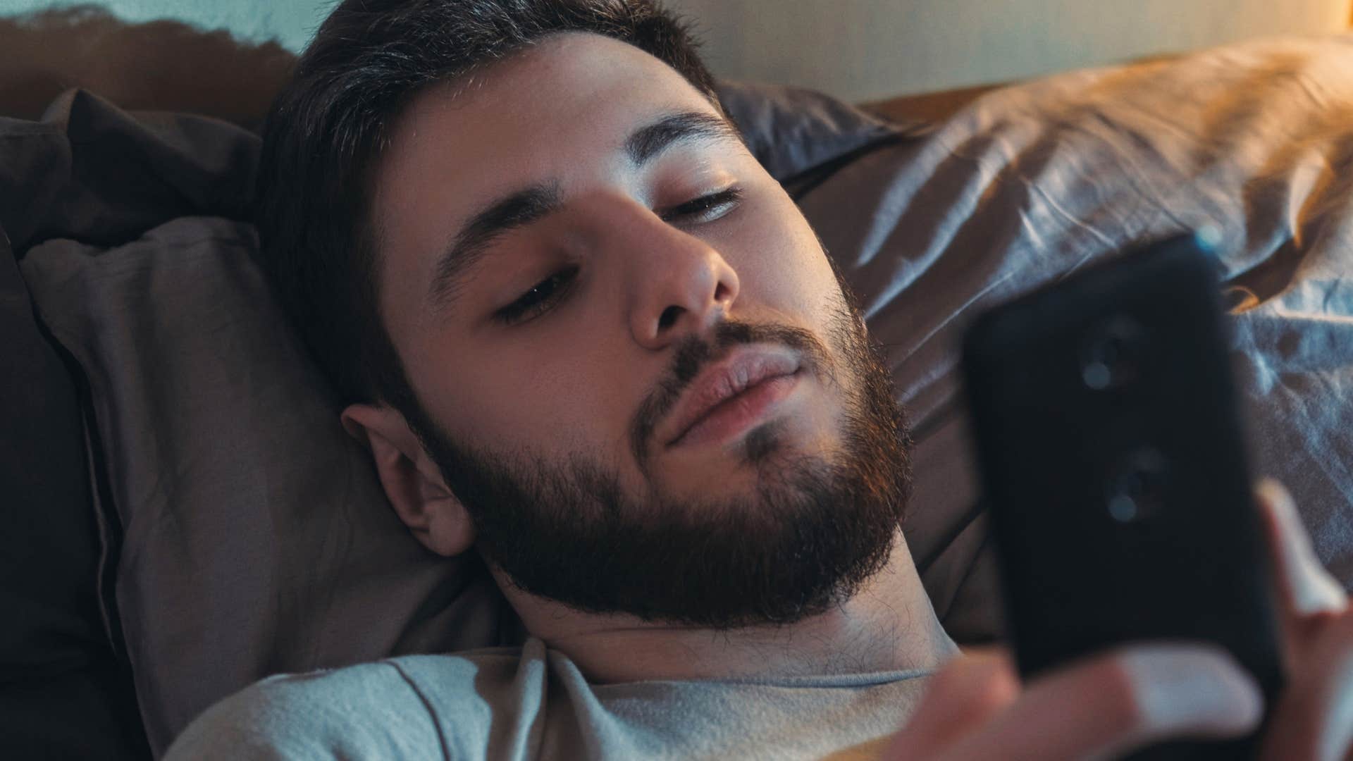 man being woken up by bedtime distractions on his phone