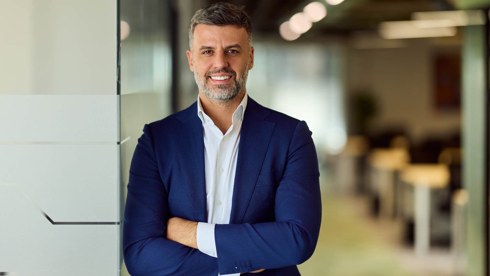 man in blue suit crossing arms as he's proactive