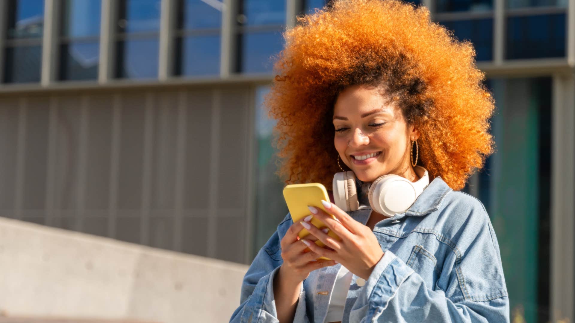 orange-haired woman who likes to experiment smiling on her phone