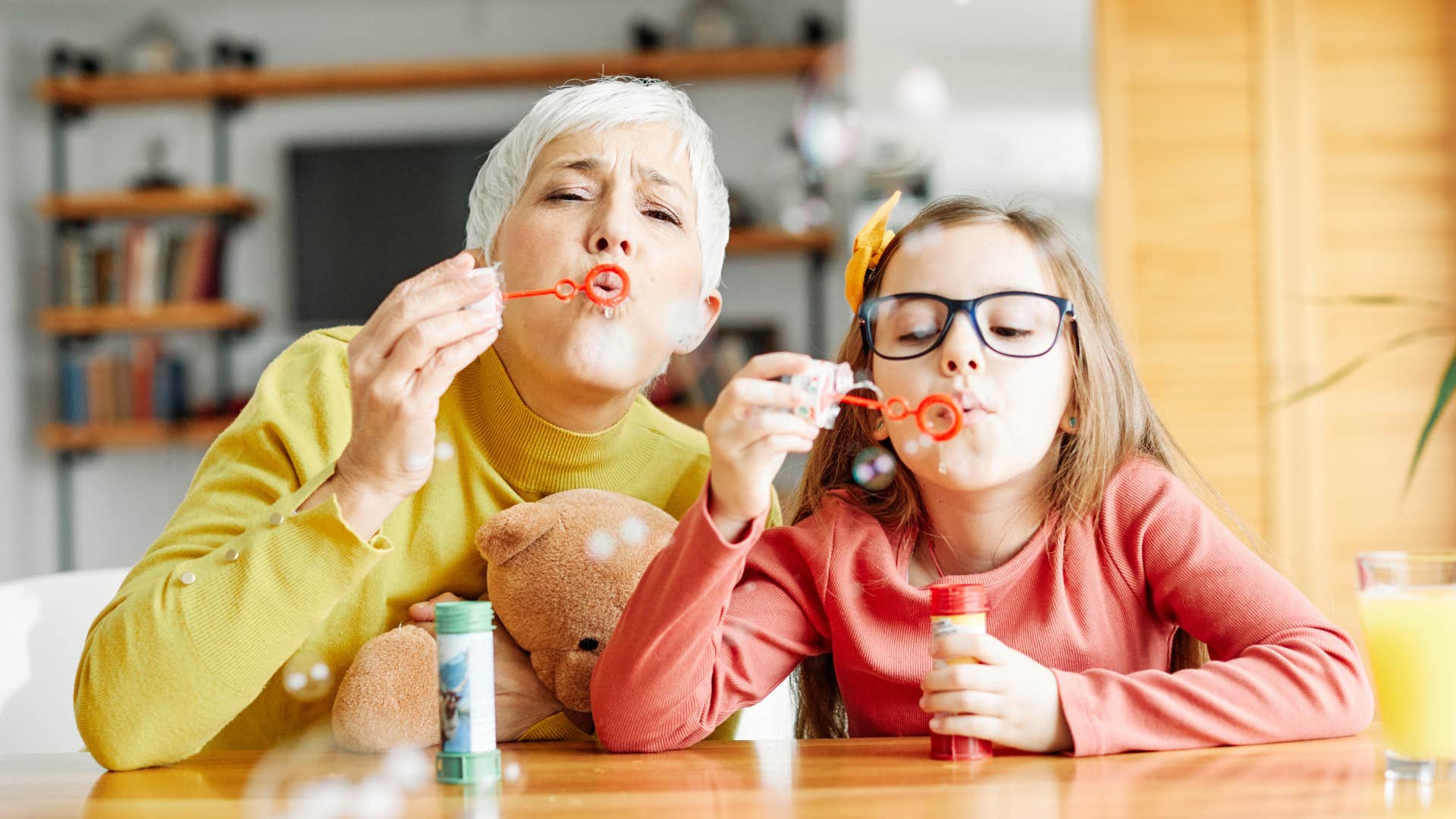 Happy older person and child blow bubbles for fun
