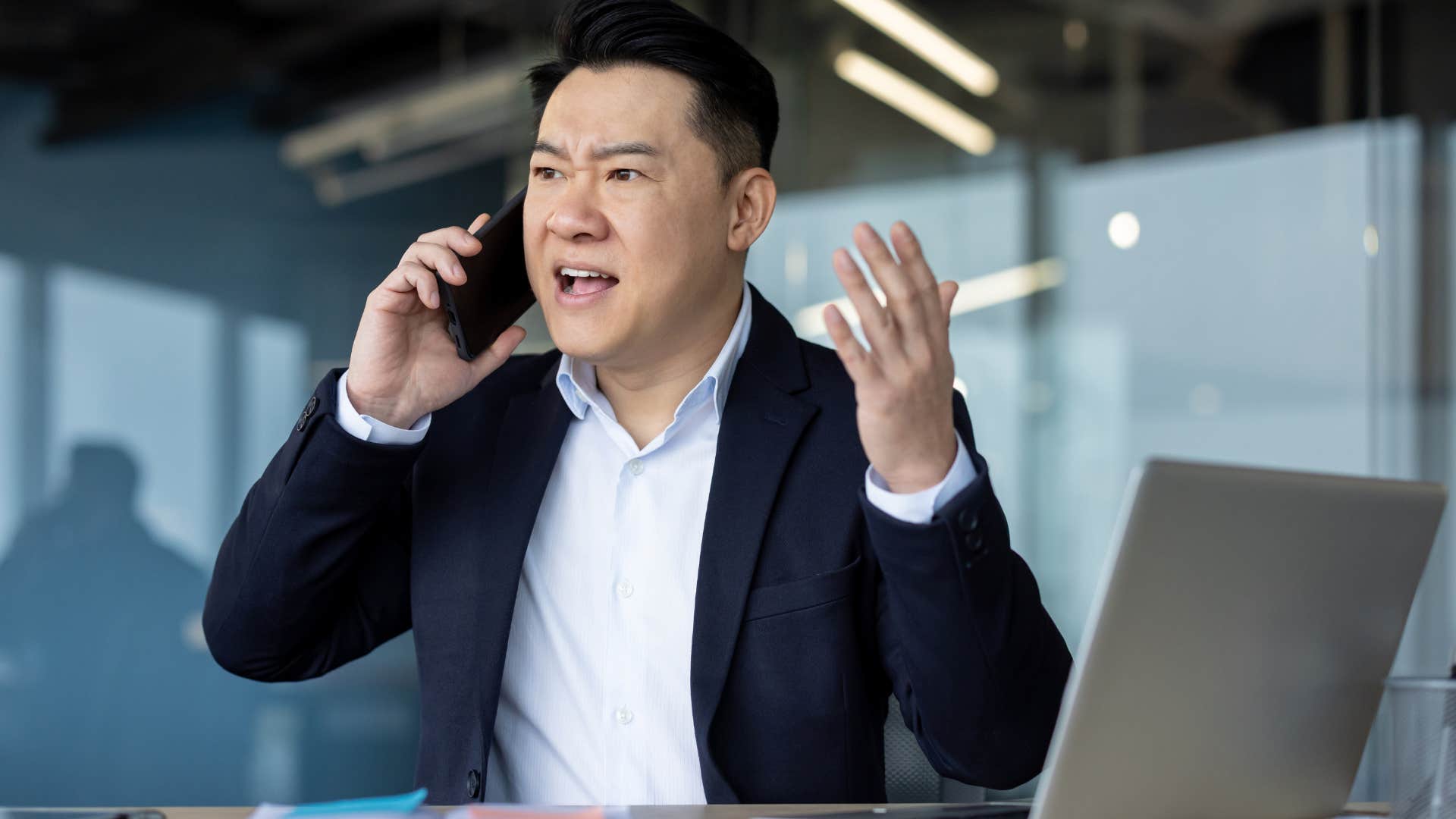 upset businessman saying people don't work hard anymore on his phone