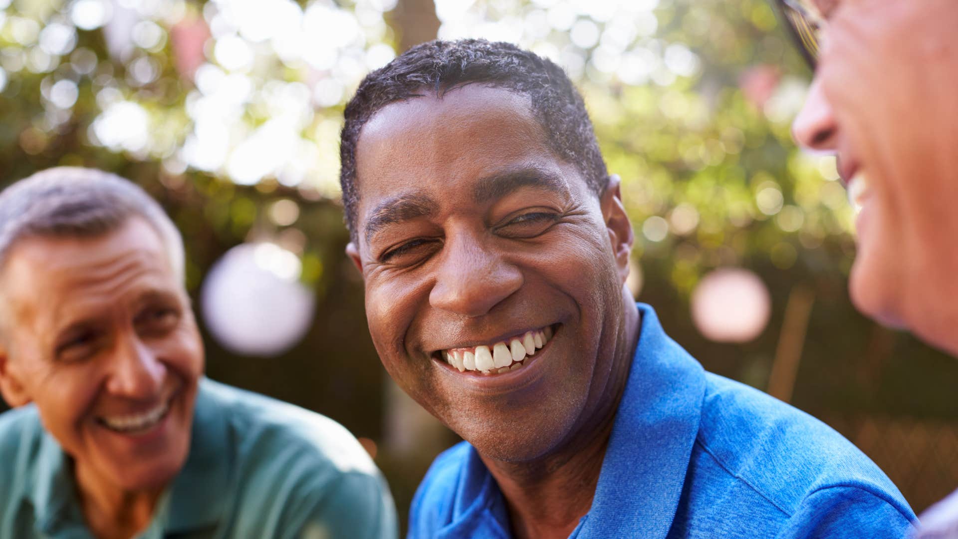 man laughing with friends reminiscing