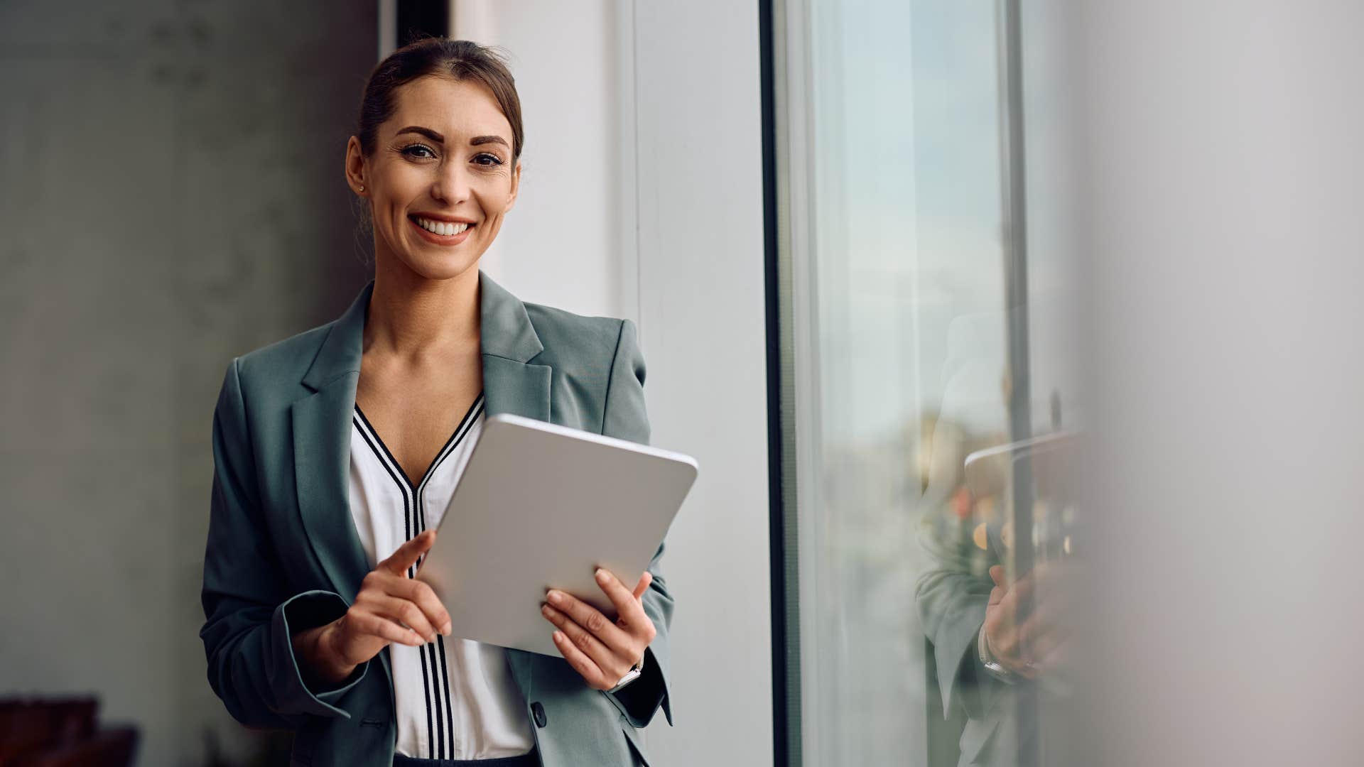 woman holding tablet standing by window