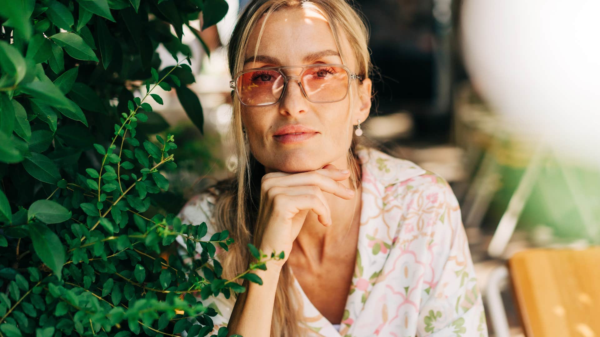 woman in sunglasses looking into camera while sitting outside