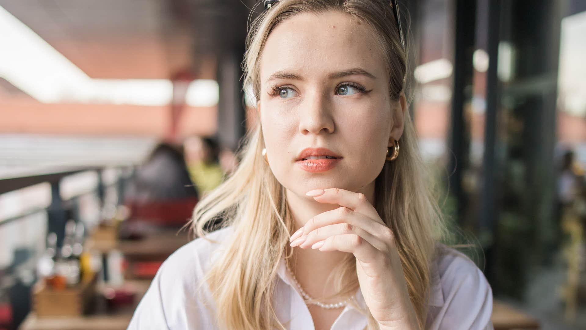 thoughtful woman sitting in cafe outside