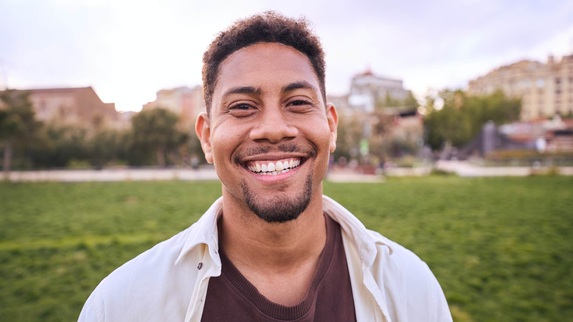 smiling man with a playful imagination standing in park outside