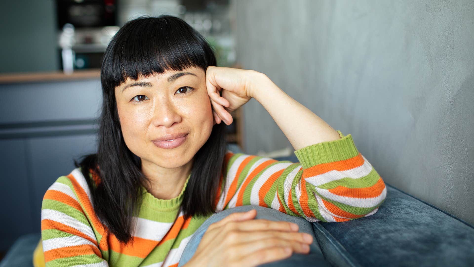 authentic woman sitting alone at home smiling