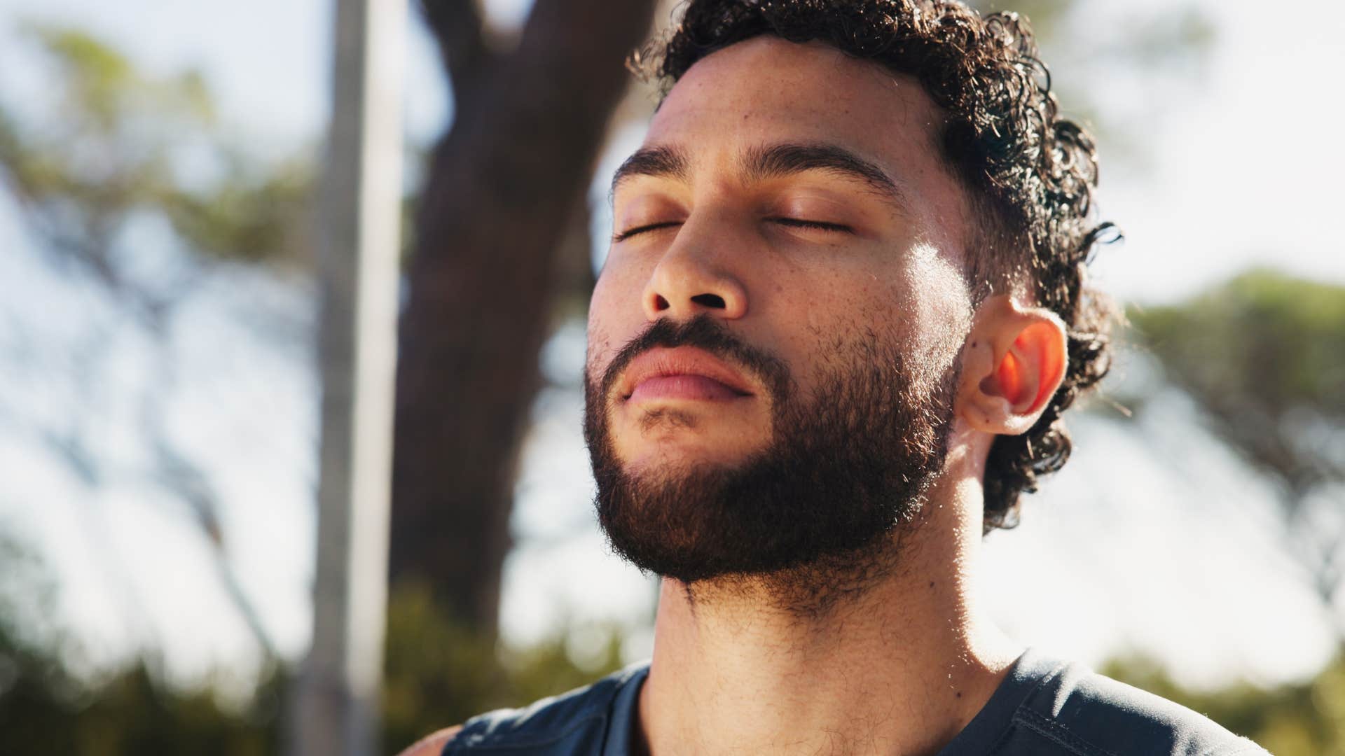 calm man standing outside with eyes closed