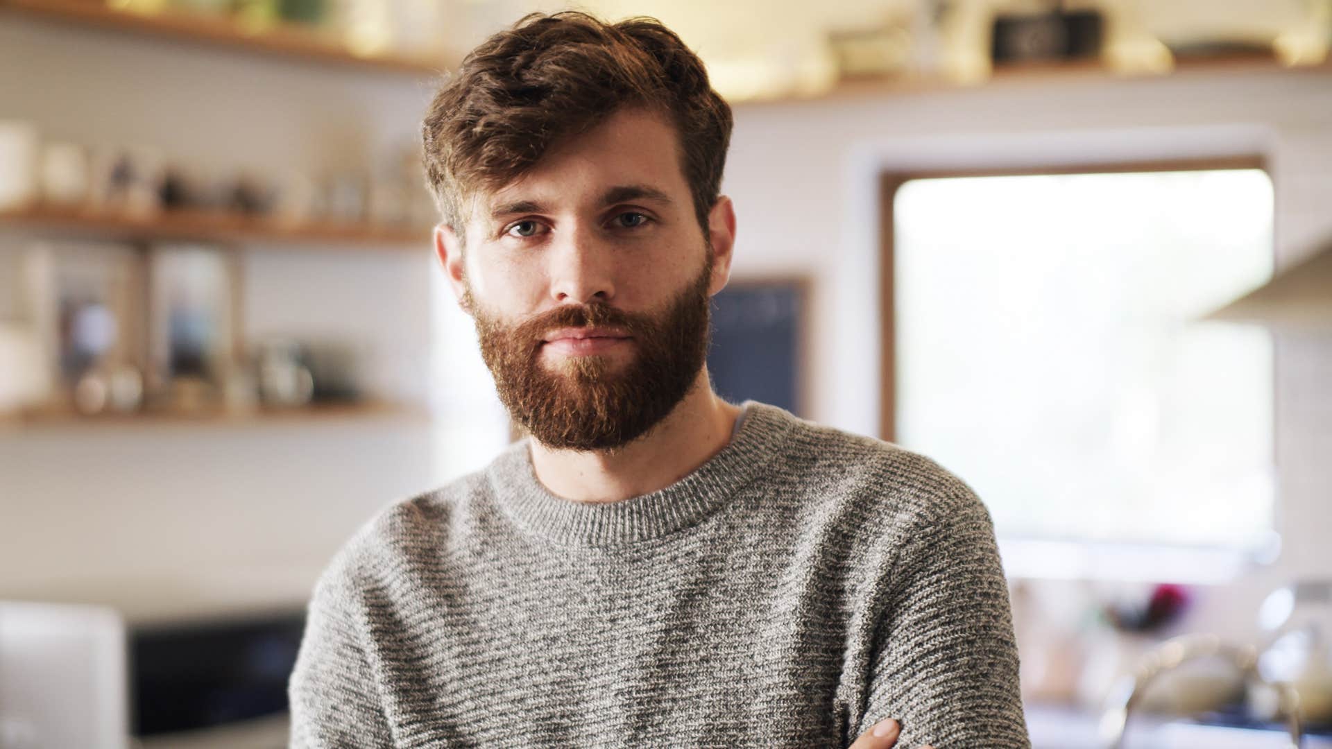 self-aware man smiling standing in kitchen at home
