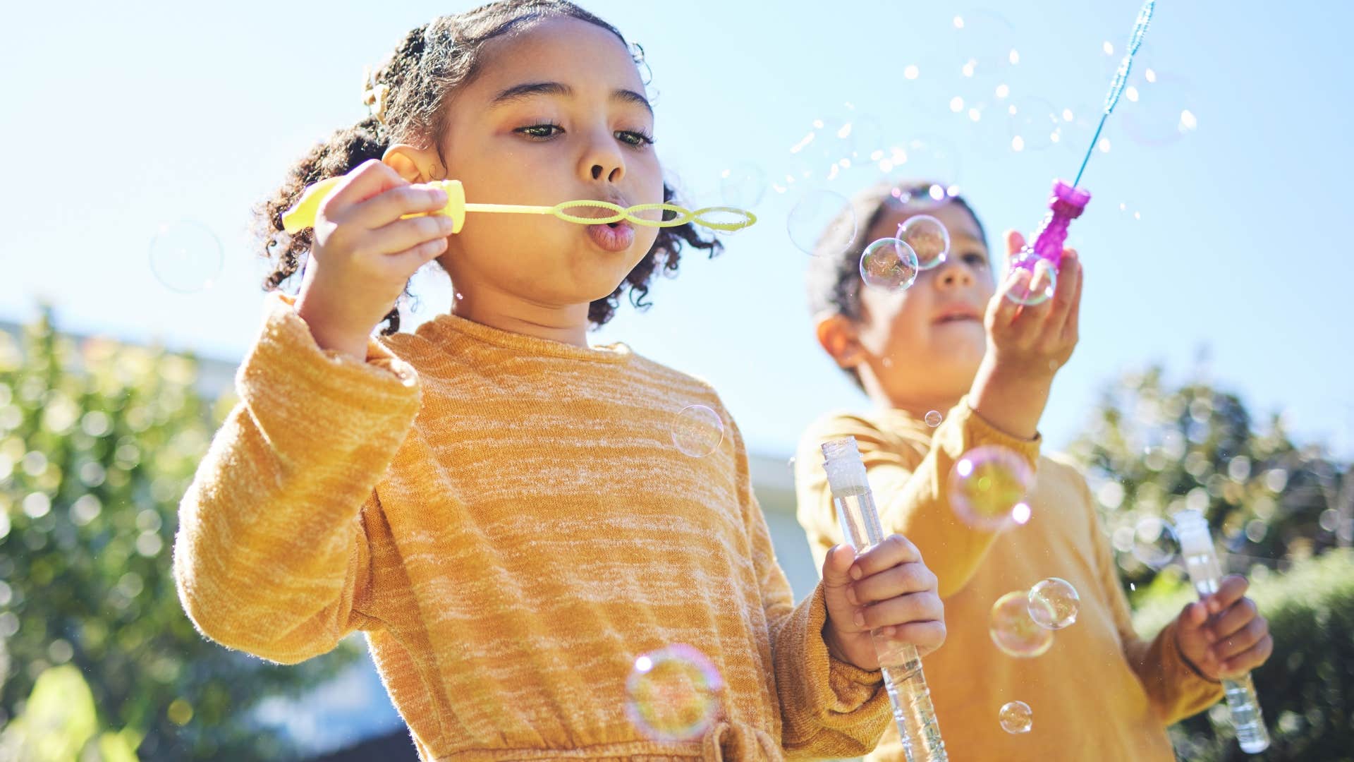 kids playing independently together outside blowing bubbles