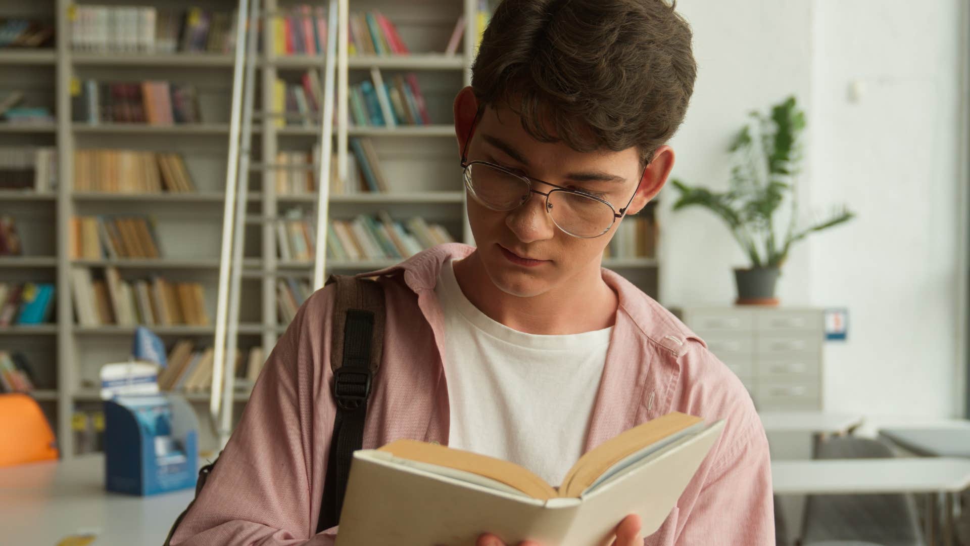 teenage boy in the 1990s reading a book and researching in library