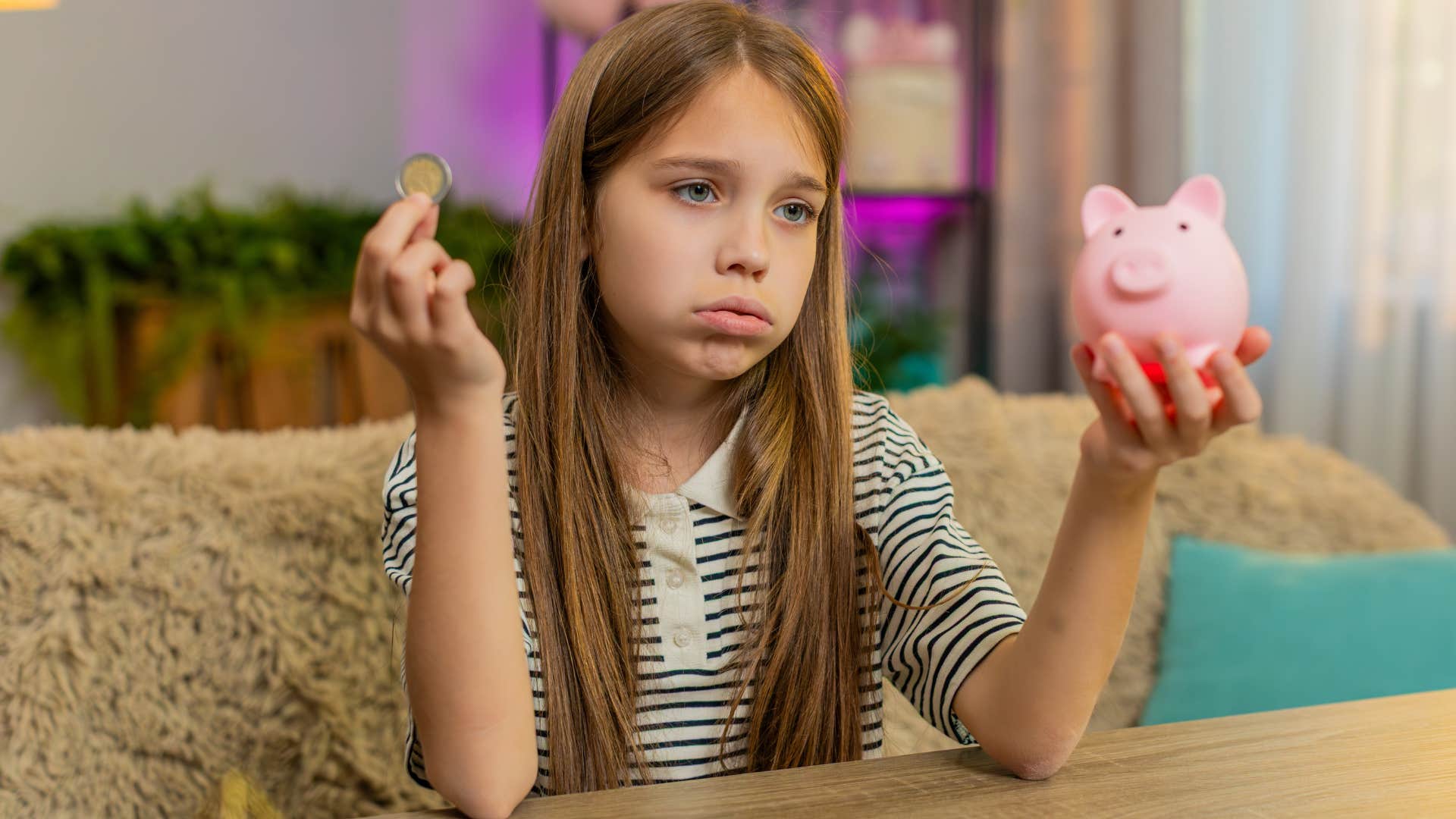 little girl waiting for things she wants saving money in a piggy bank