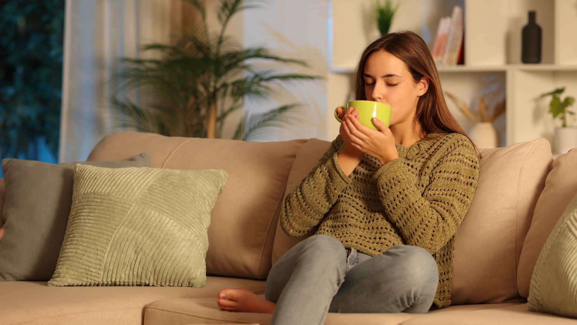 woman drinking coffee sitting on couch