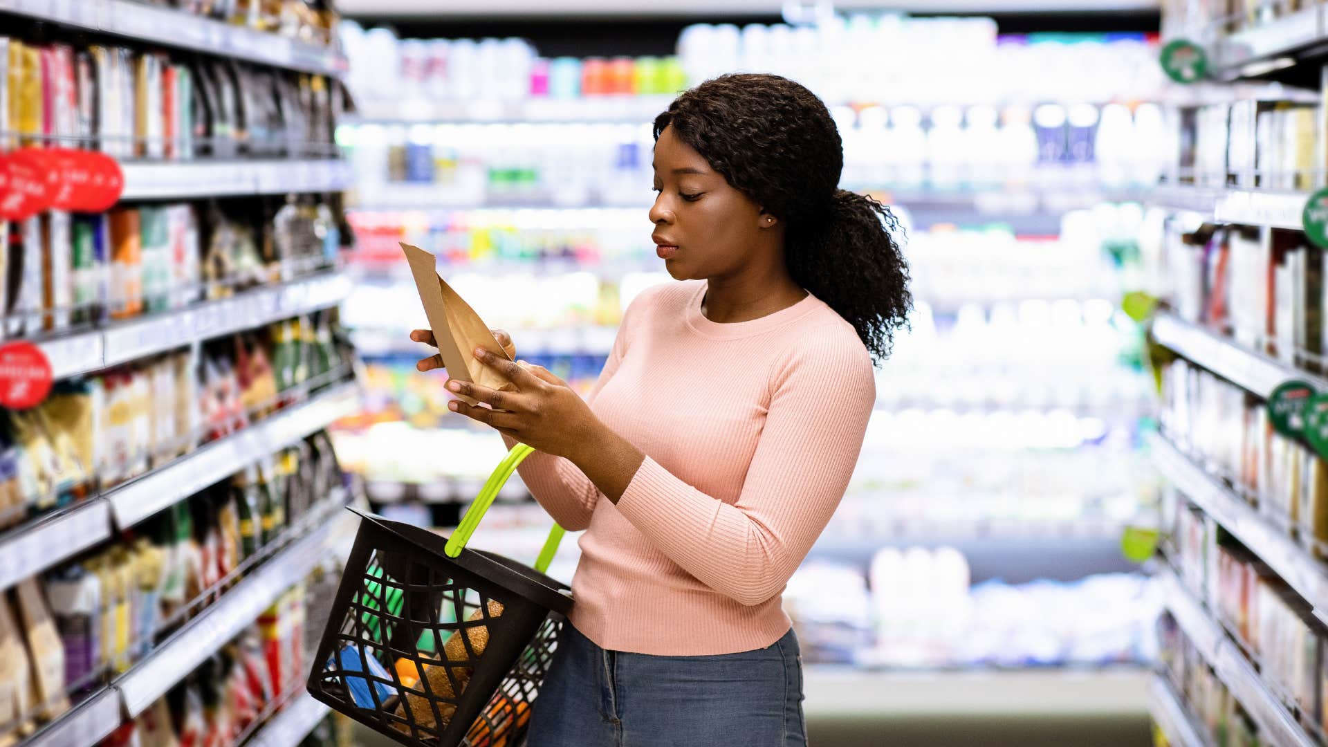 young woman grocery shopping noticing how expensive everything feels