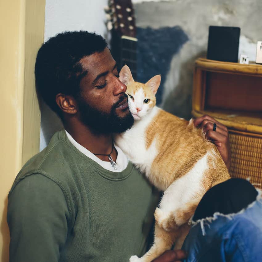 man happily single snuggling with cat