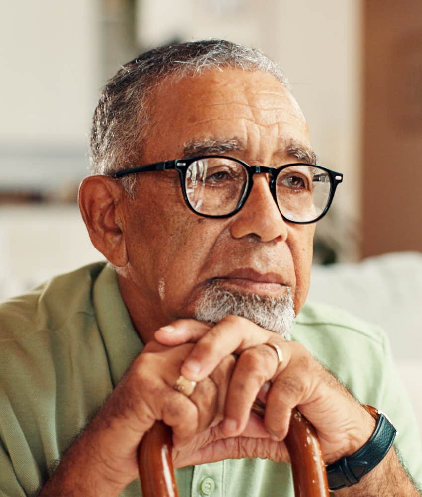 introspective elderly person rests head on cane showing worked too hard in life