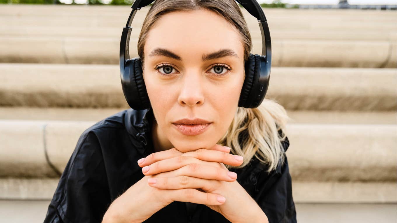 A young blonde woman sitting on stairs with headphones on, illustrating the 'internal focus' and mindfulness needed to listen to your gut instincts.