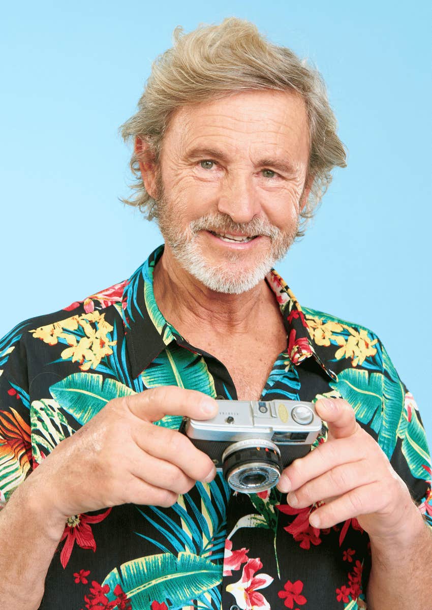 smiling older man holding camera doing what he enjoys