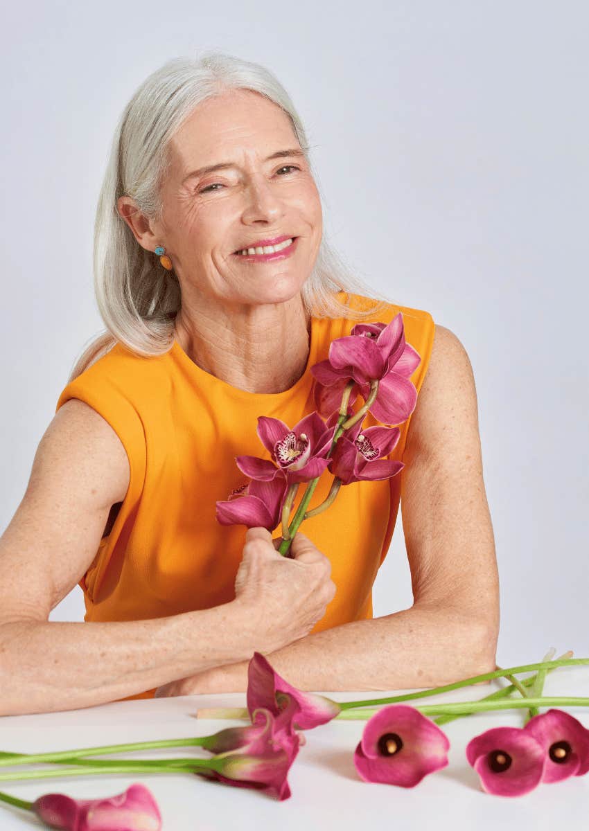 smiling wise older woman holding flower