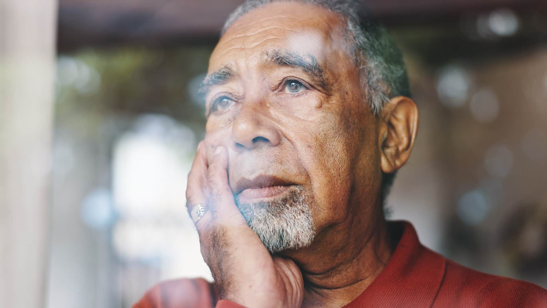 self-critical man looking out the window longingly