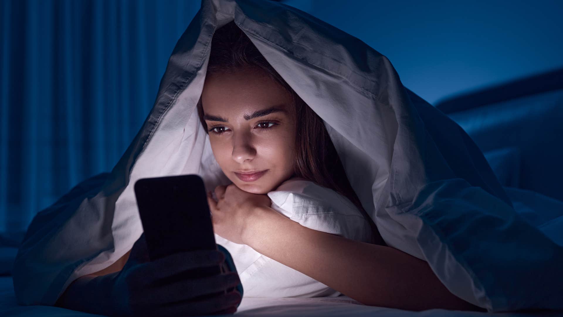 Woman who craves comfort and escape sitting in bed with her phone.