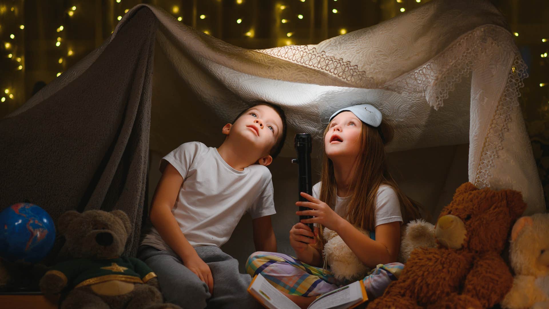 two kids sitting in fort they built in the backyard