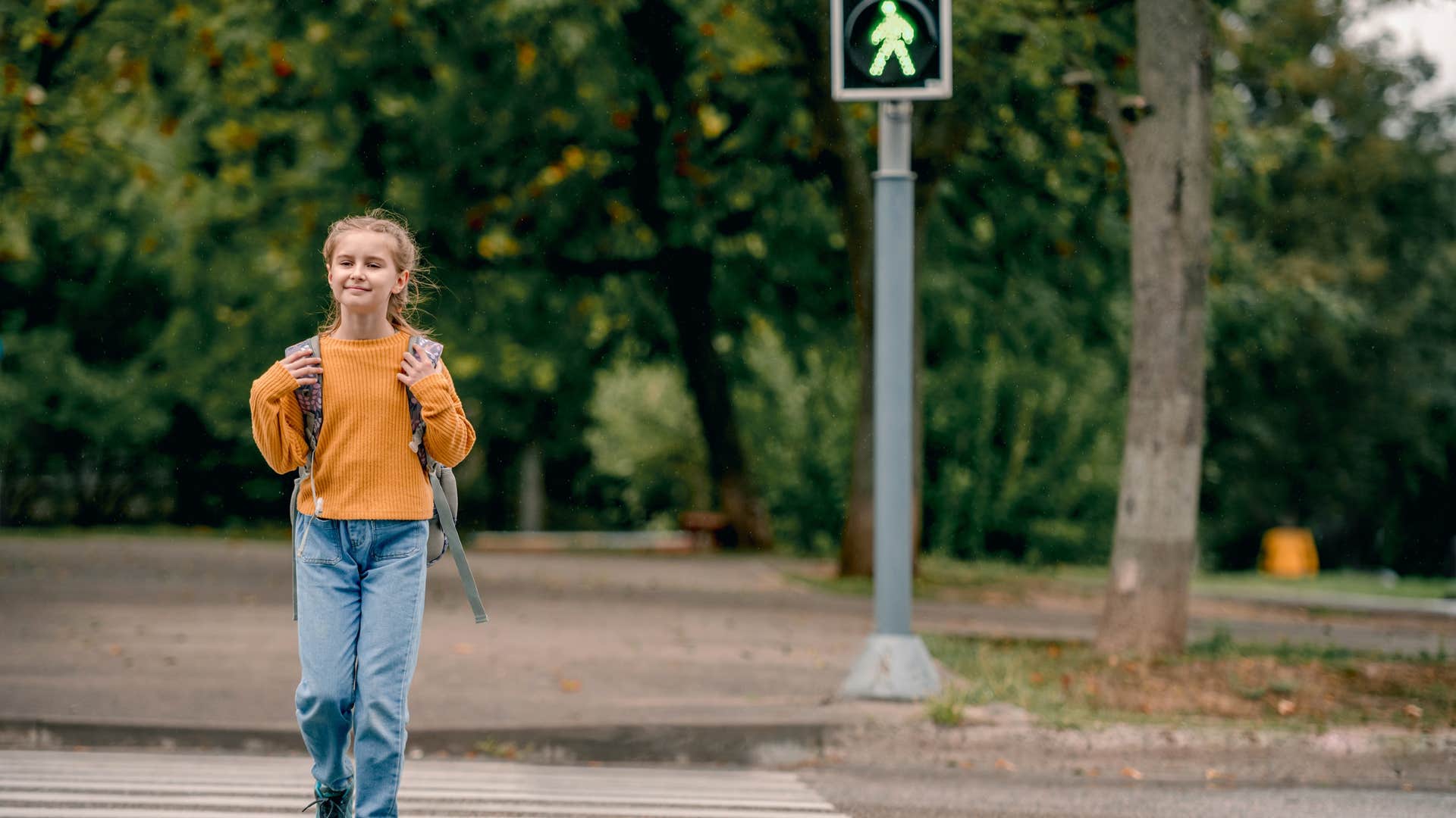 girl crossing the street walking home from school alone