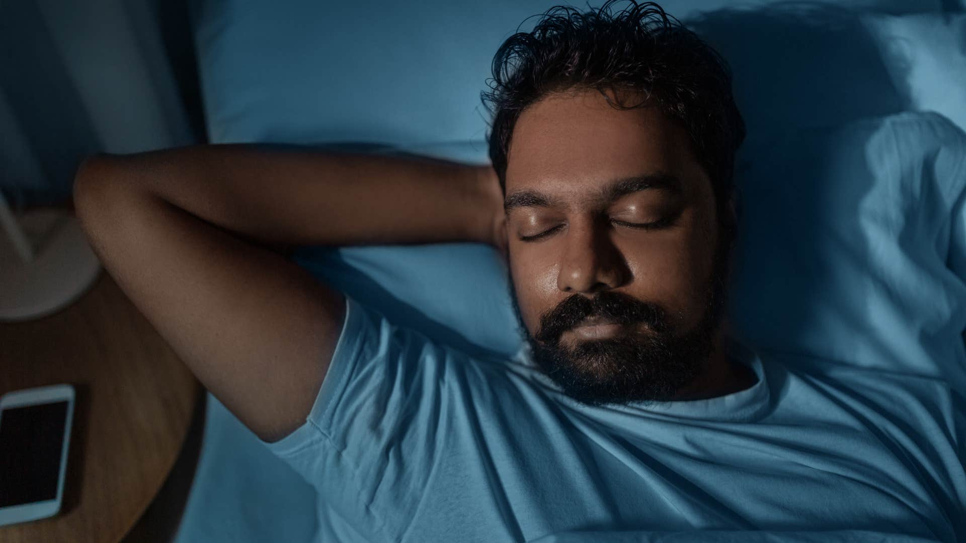 man laying in bed going to sleep earlier than he thinks