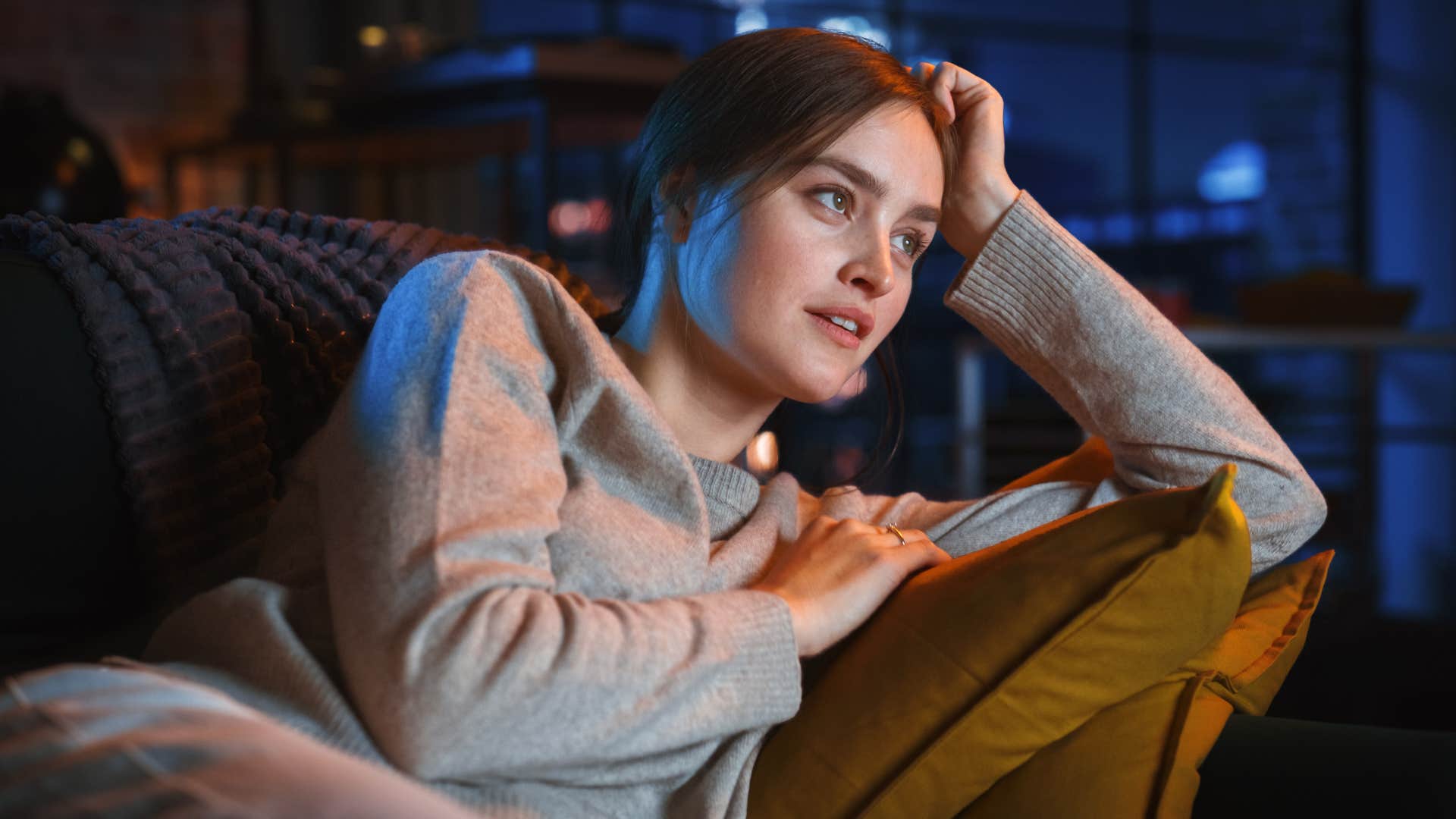 woman watching television on her couch
