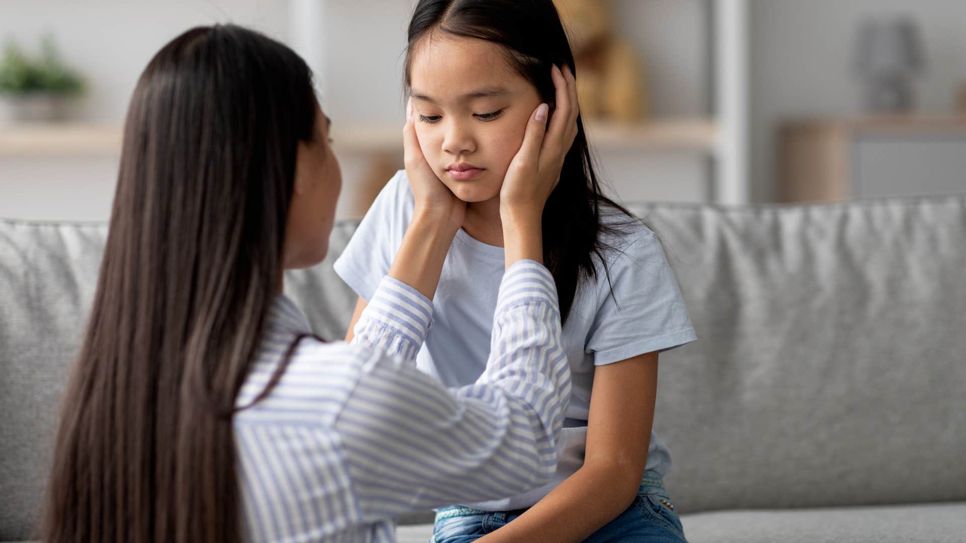 mom cradling upset daughter's face minimizing her feelings