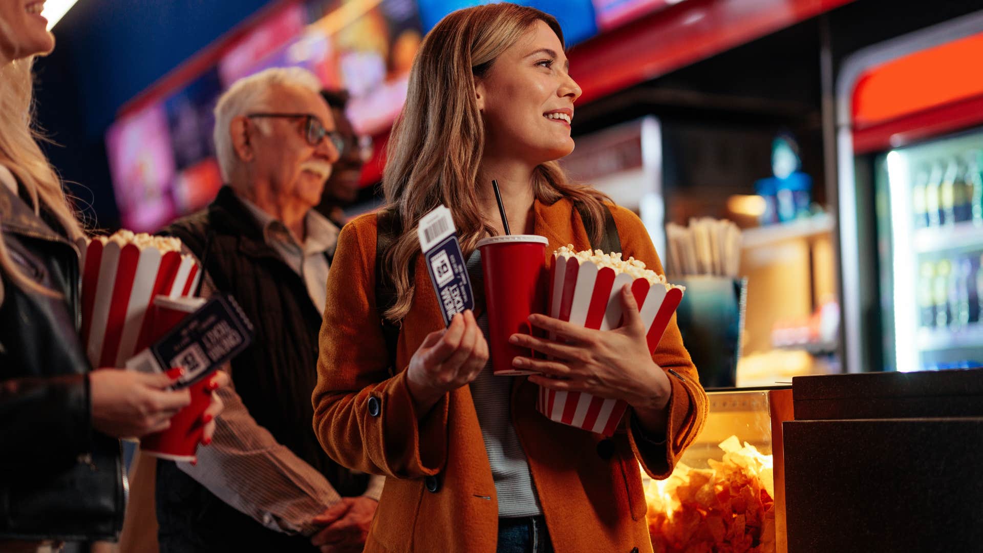 woman holding movie tickets and snacks at the theater