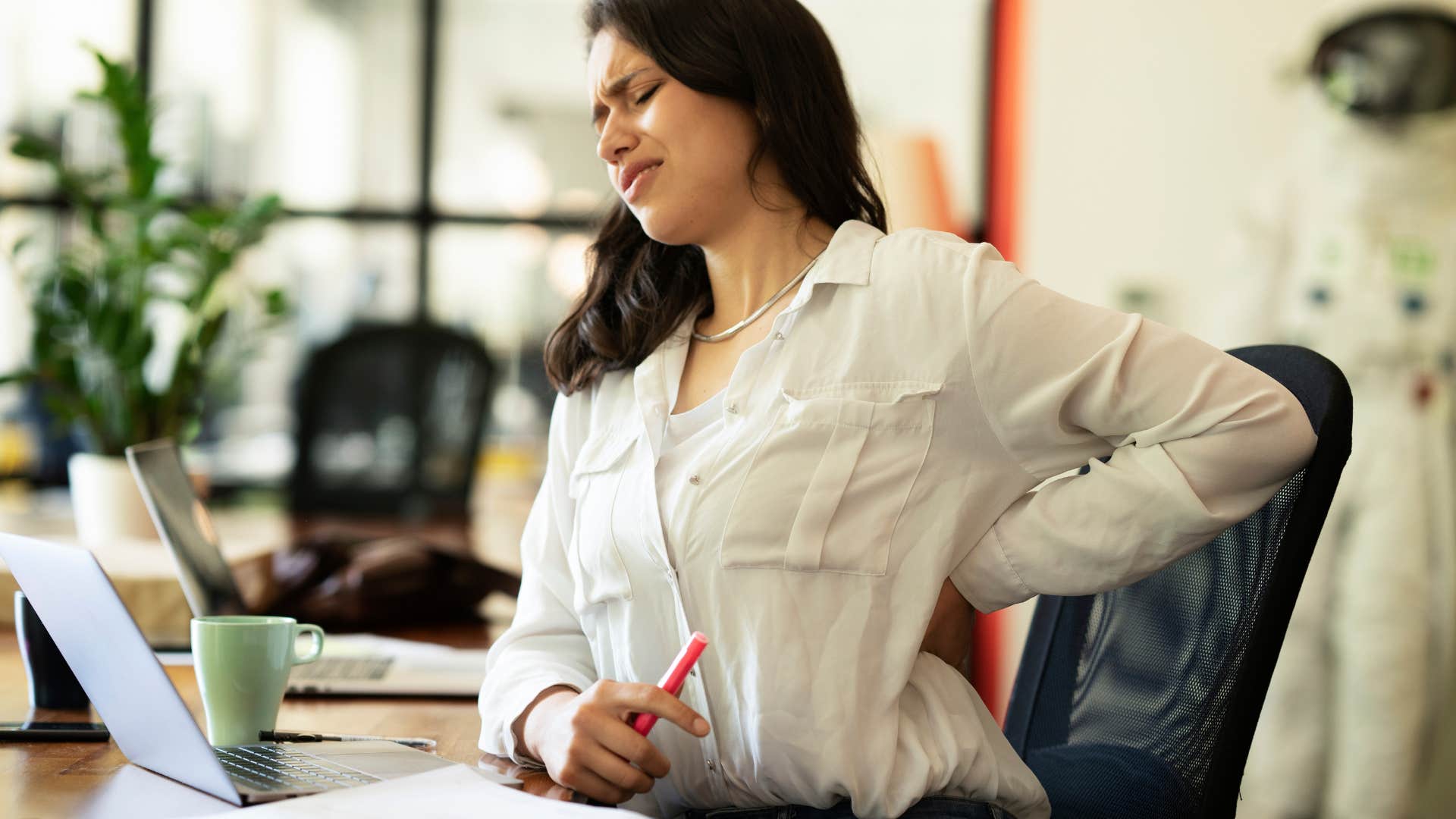 woman in pain sitting at desk
