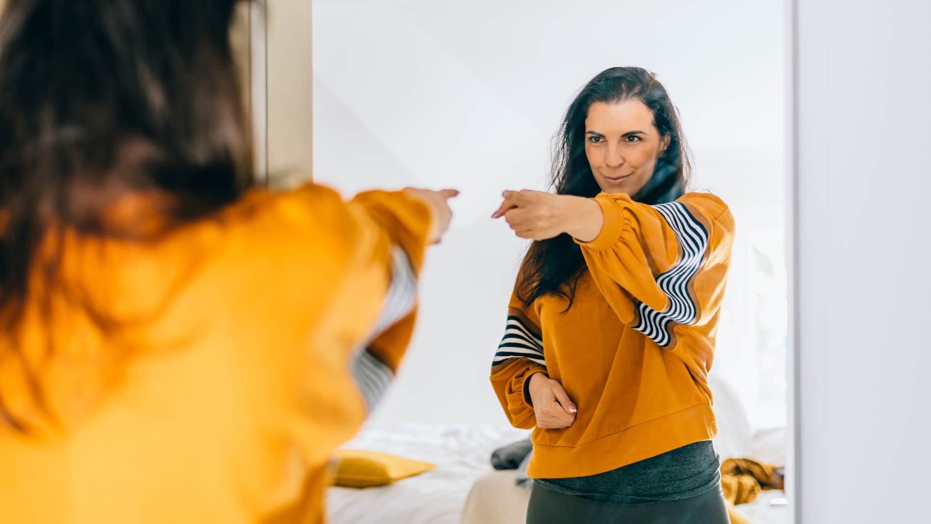 happy woman giving herself a positive pep talk in mirror