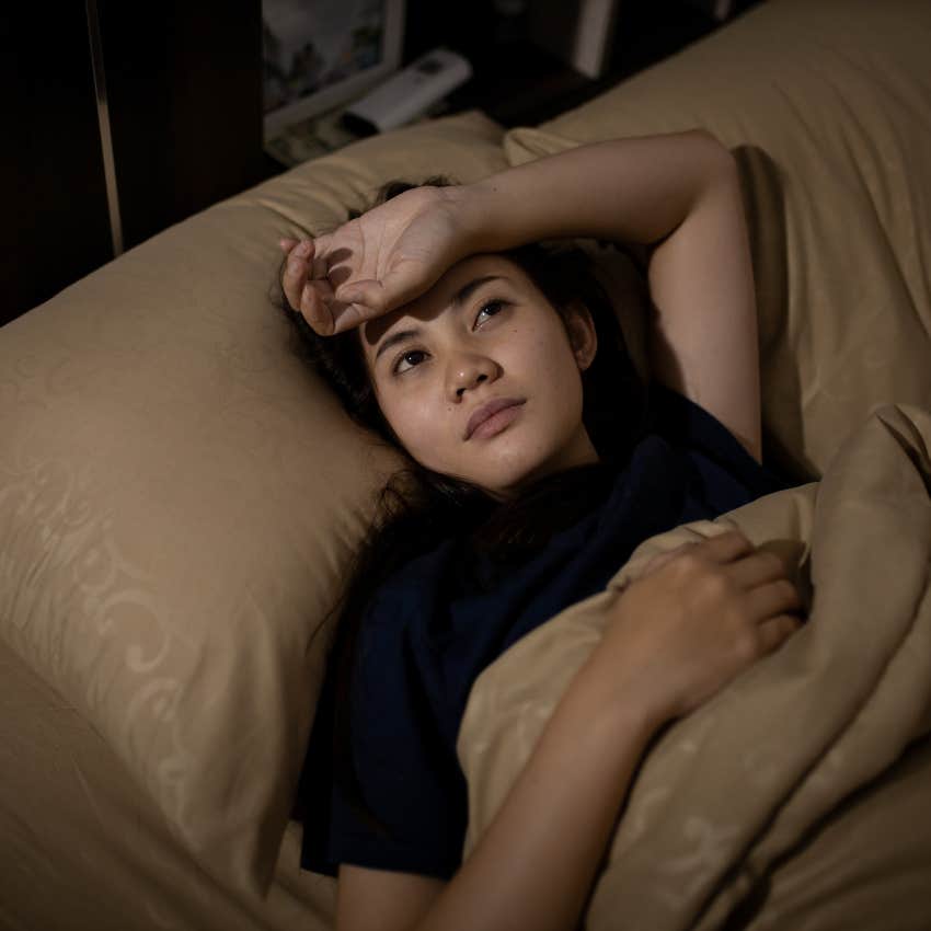 woman who doesn't sleep well laying in bed stressed